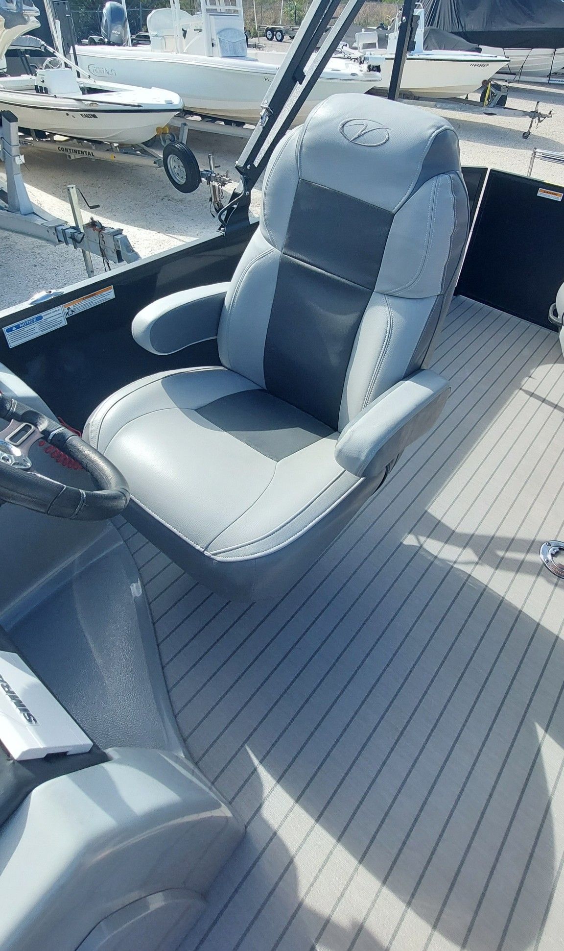 Padded gray captain’s chair on a boat deck with docked boats in the background