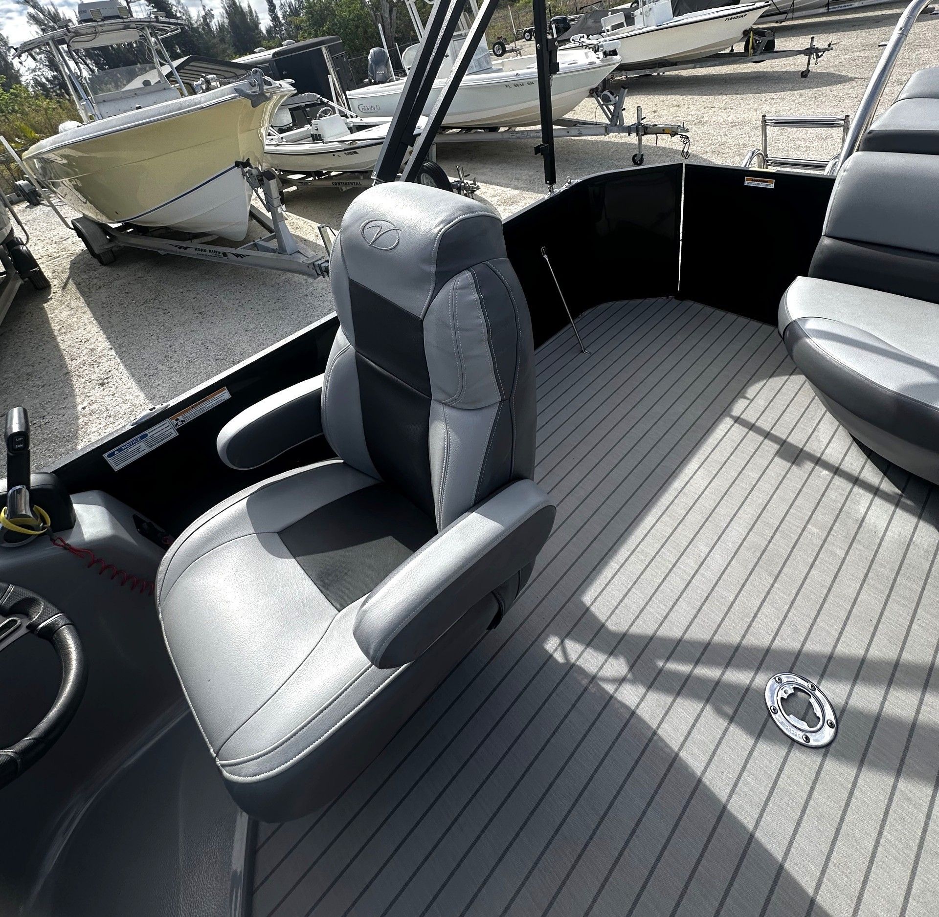 Boat cockpit with gray captain’s chair and black seating on a docked vessel under bright sunlight