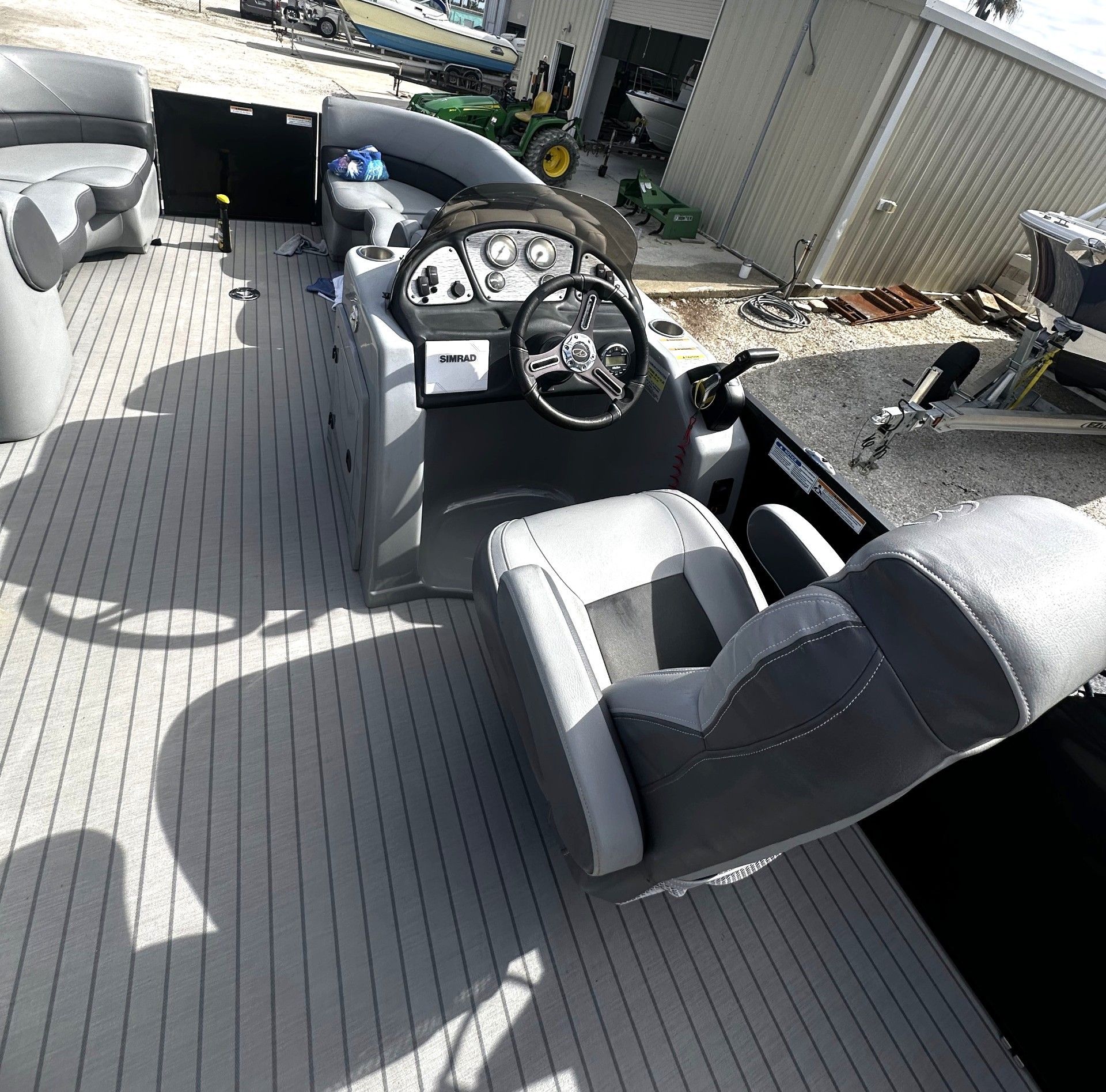 Boat cockpit with steering wheel and gauges, gray seats, and a carpeted deck in sunlight