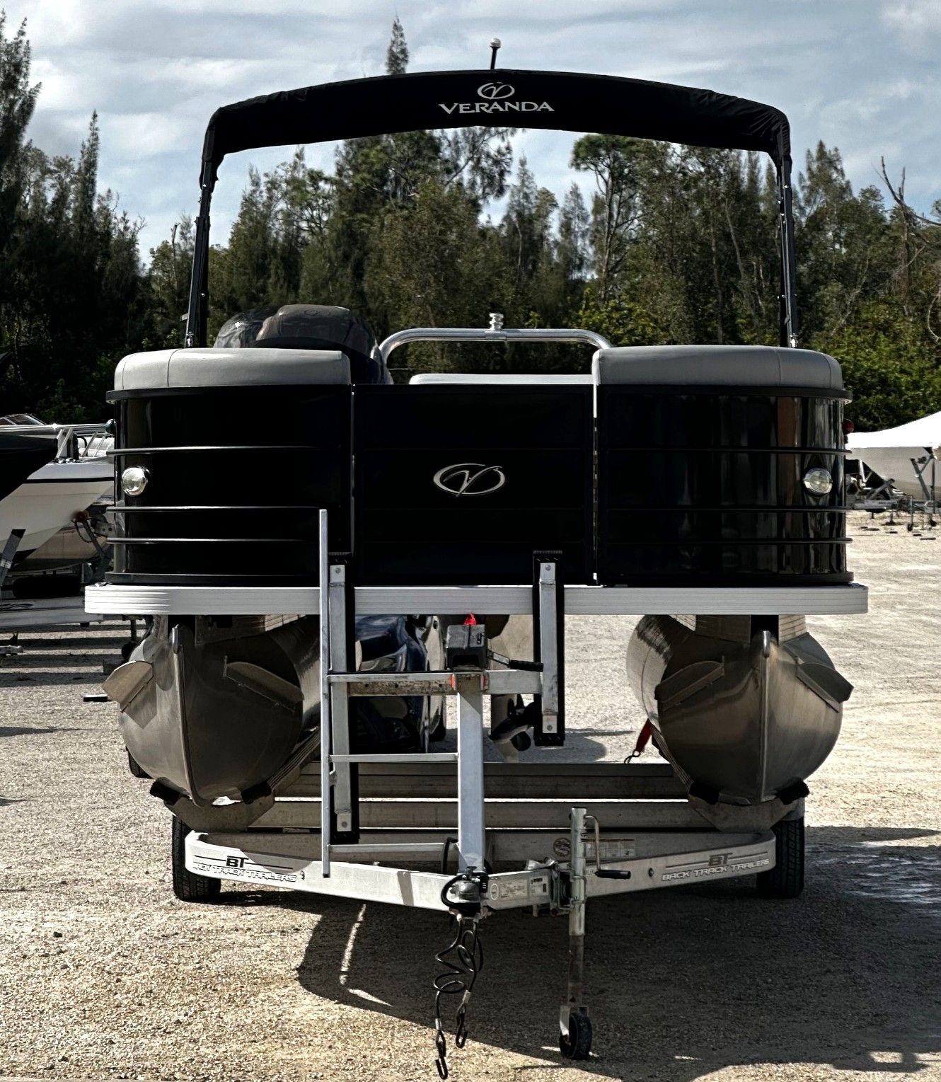 Pontoon boat with black canopy and gray seating on a trailer outdoors