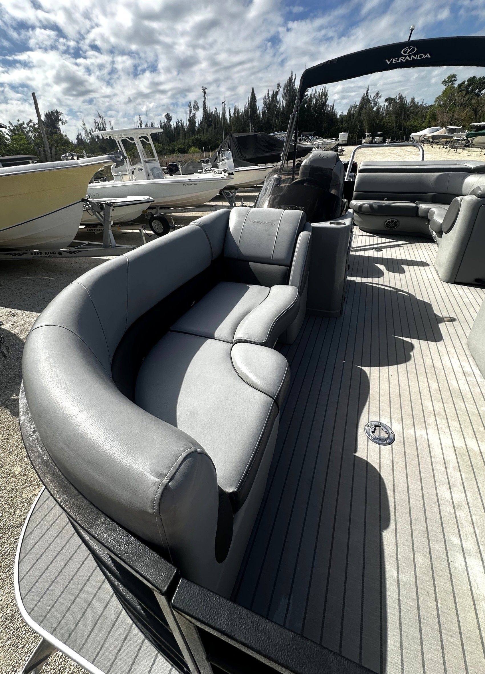 Gray curved boat seating on a docked pontoon boat under a sunny sky.