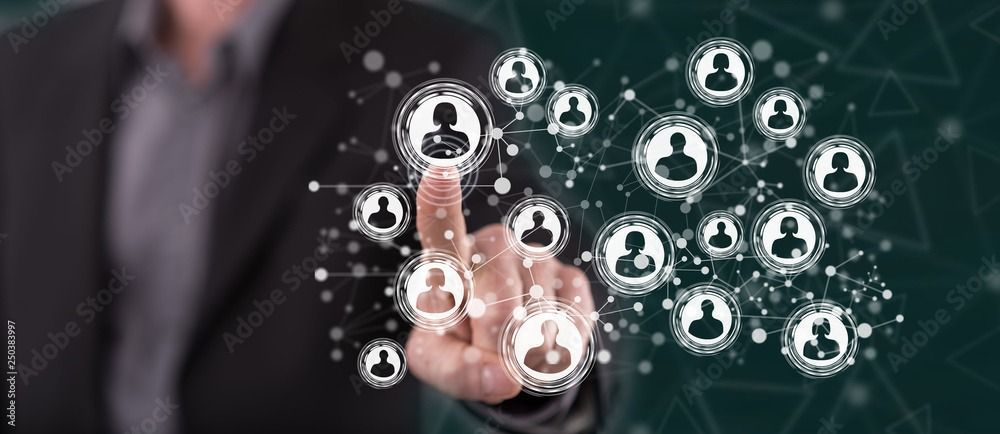 A person in a suit touches a digital, glowing network of interconnected user profile icons against a dark green background.