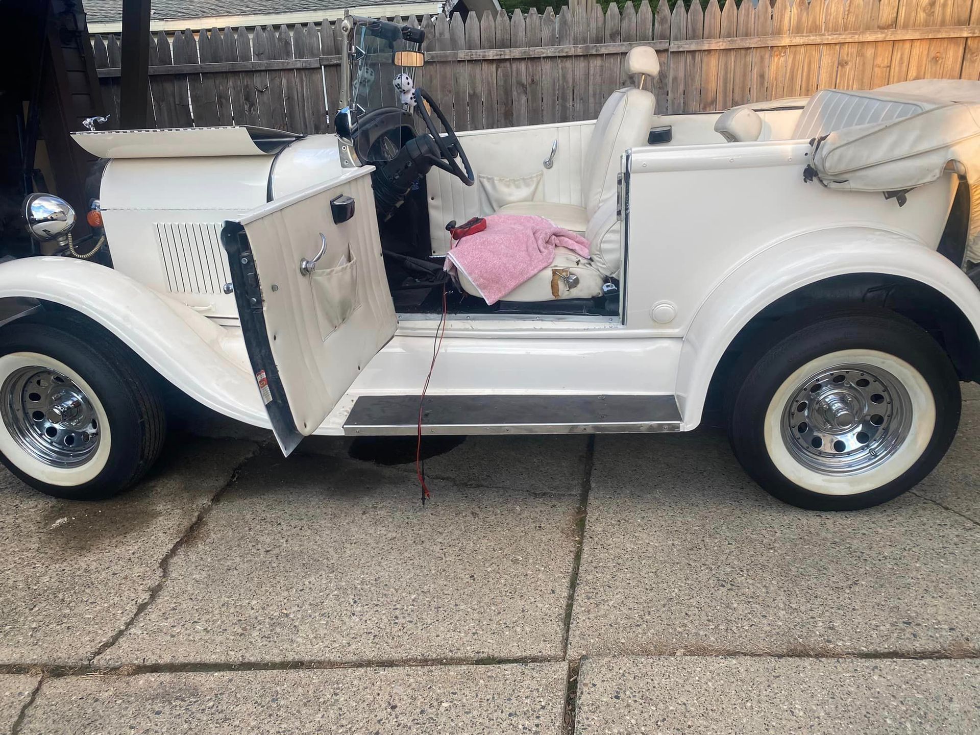 A white car with the door open is parked on a sidewalk