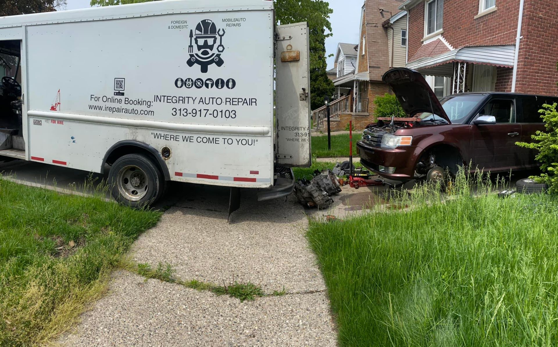 A white truck is parked in front of a house with the hood up.