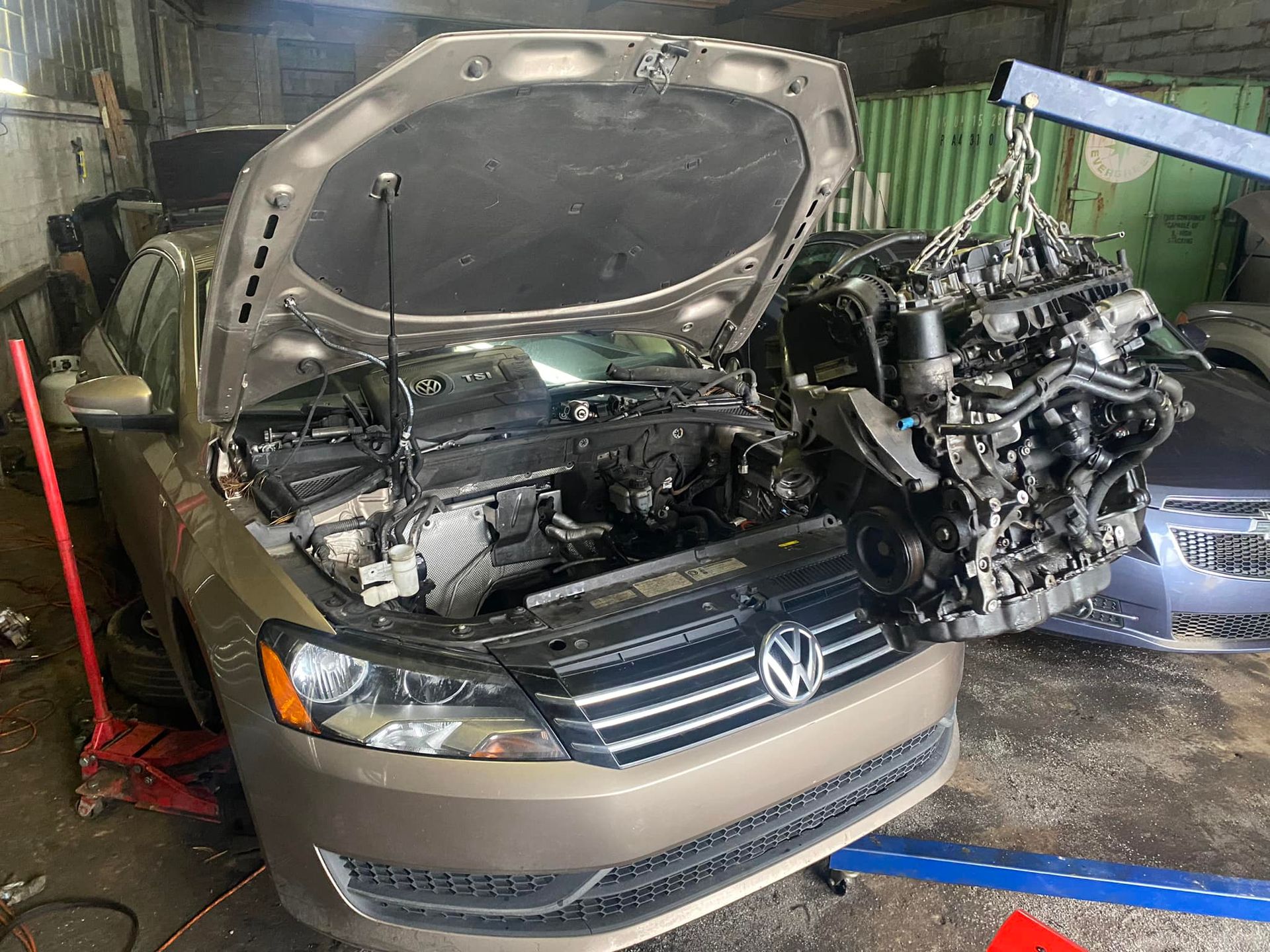 A car with its hood open is being worked on in a garage.
