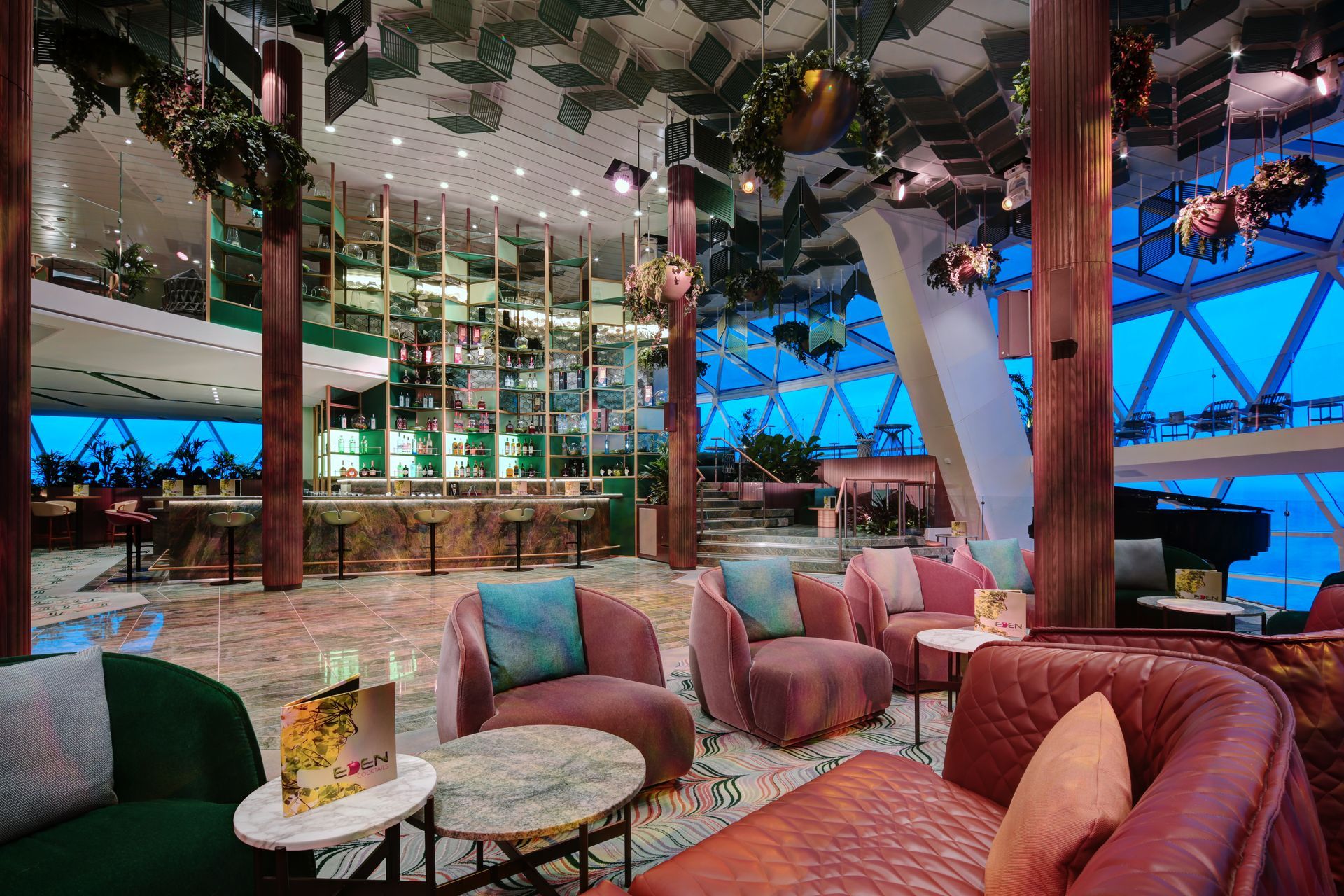 Luxurious bar with seating, potted plants, a grand piano, and a glass wall with ocean views.