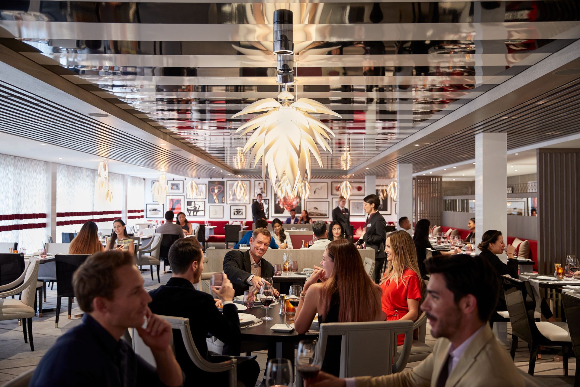 Restaurant interior with diners seated at tables. Mirrored ceiling, white walls, and bright overhead lights.