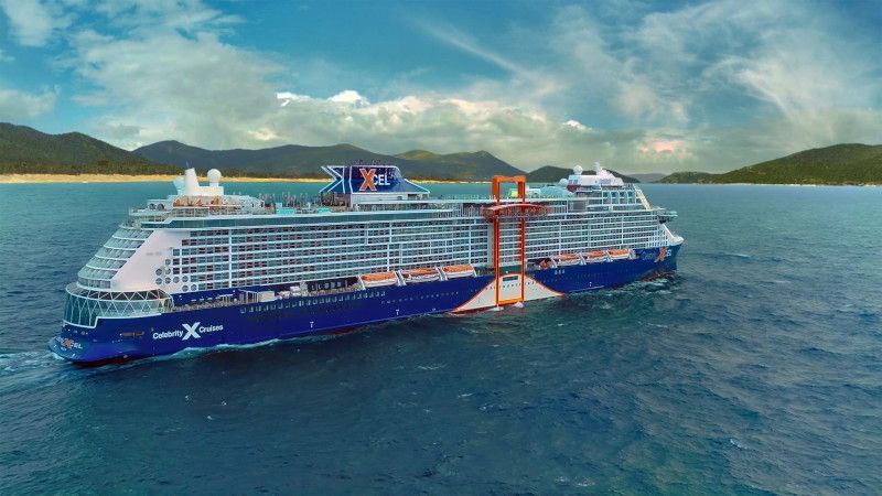 Large blue cruise ship sailing on a body of water with land in the background.