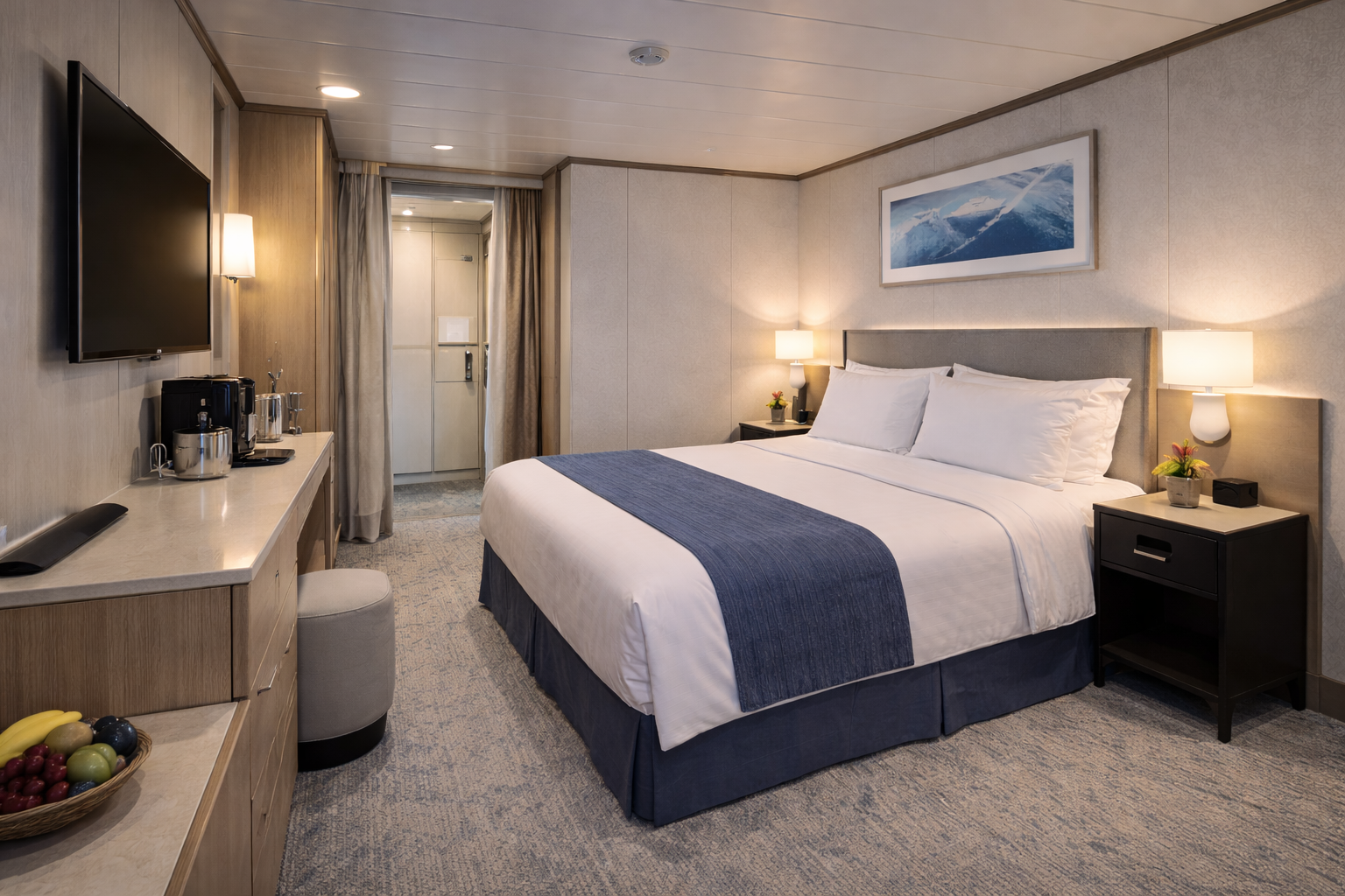 A well-lit cruise ship cabin with a bed, desk, TV, and small bathroom visible in the background.