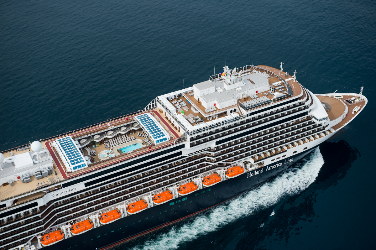 Cruise ship sailing on dark blue water, seen from above.