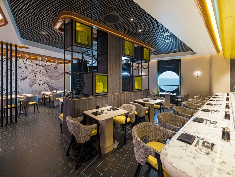 Modern sushi restaurant interior with yellow and gray accents, seating area, bar, and ocean view.