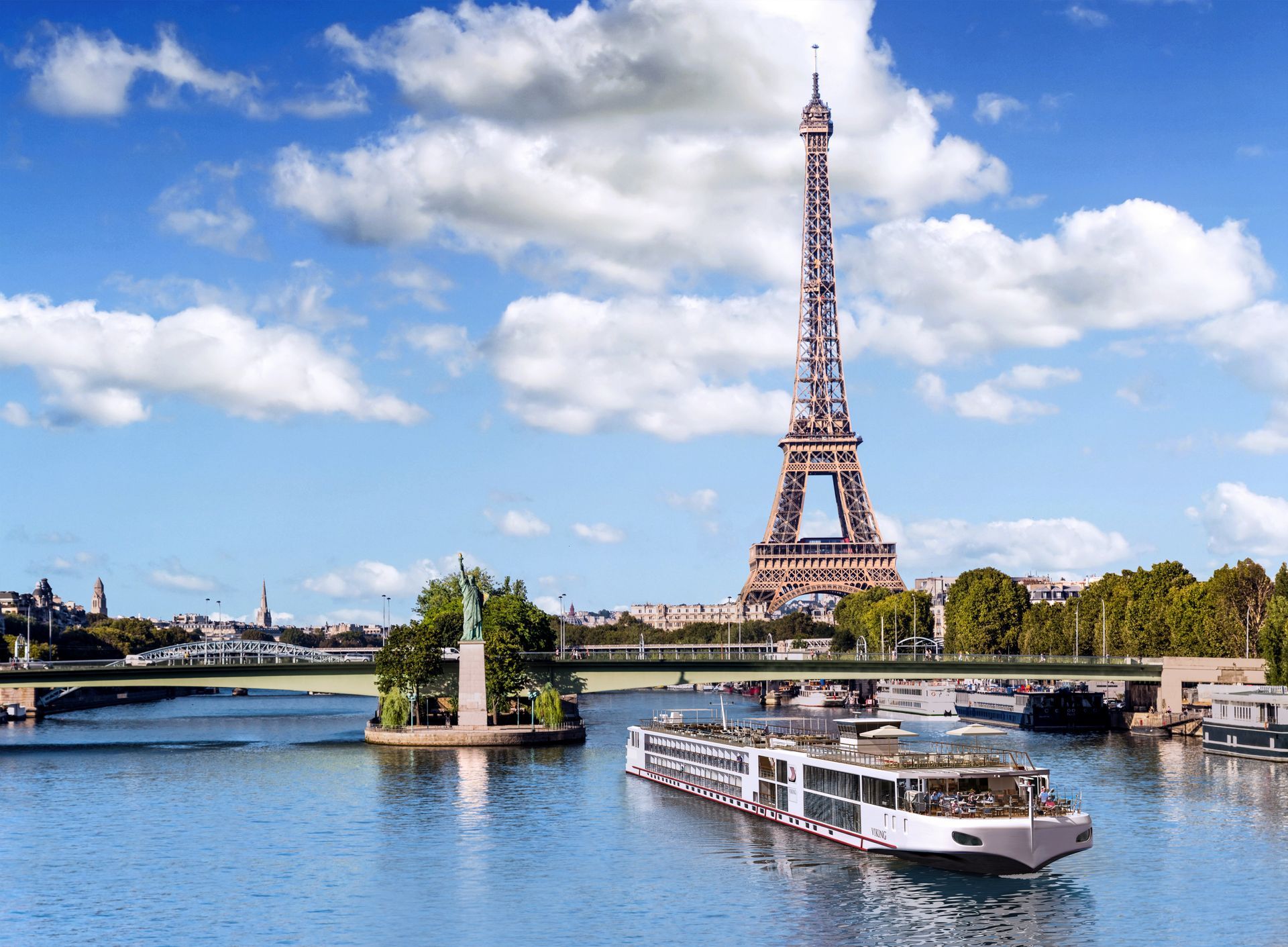 Eiffel Tower in Paris, France, with a riverboat on the Seine. Blue sky, water, and bridge.