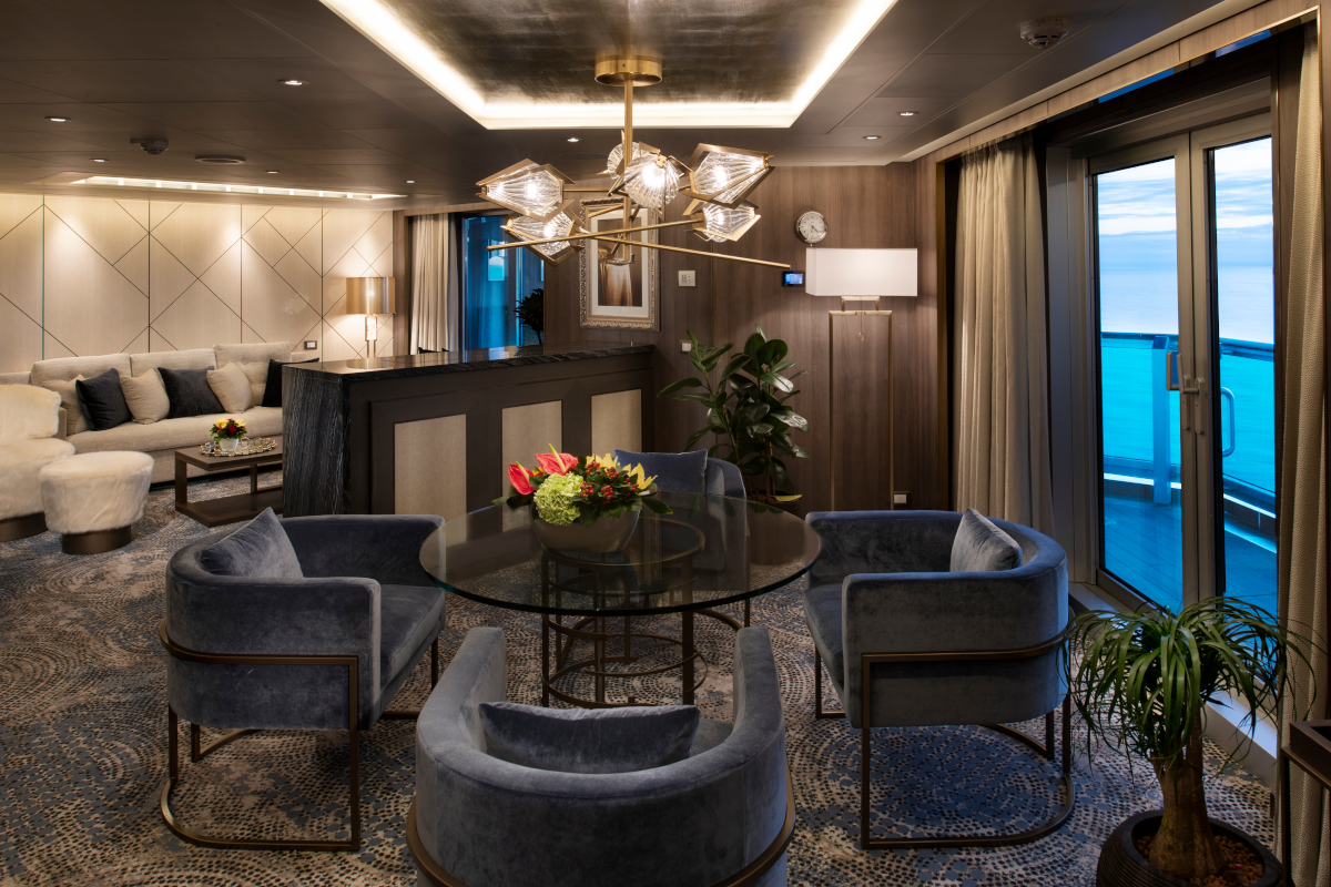 Luxurious cruise ship suite with dining area and ocean view.