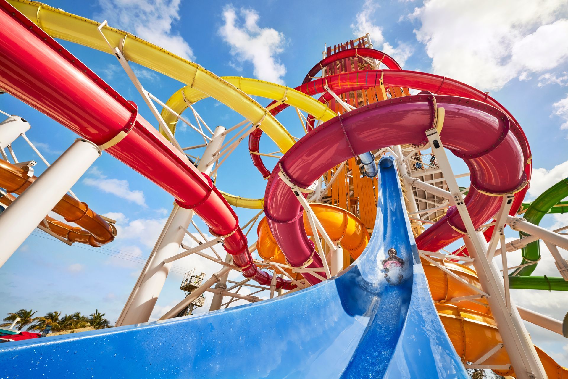 Colorful water slides at a water park, including red, yellow, and blue slides against a blue sky.