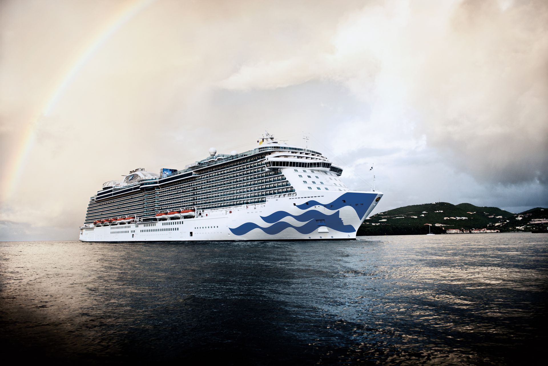 Cruise ship with blue wave design sailing on water, rainbow in sky.