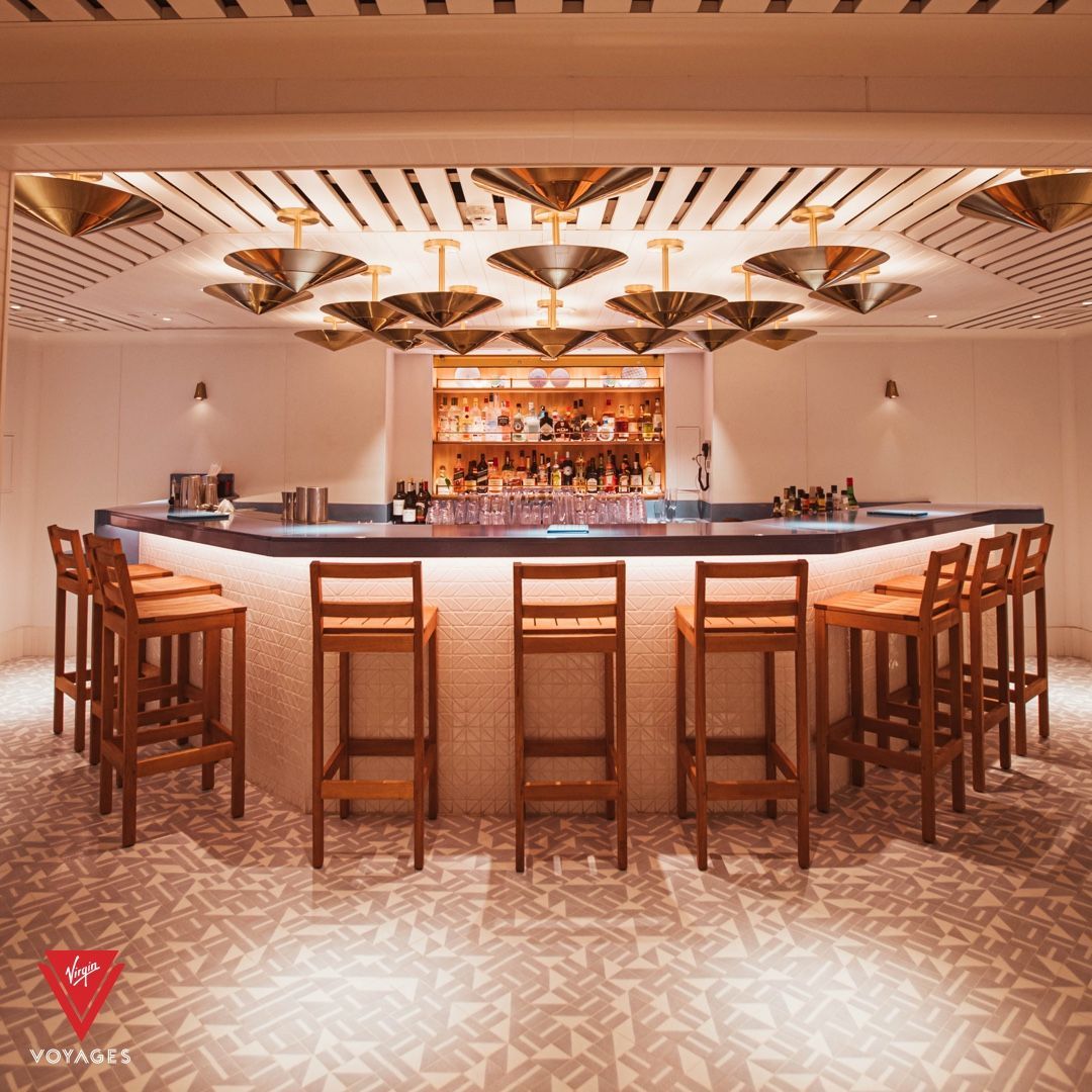 Bar interior with stools, drinks, and decorative ceiling lights at The Dock - Virgin Voyages' dedicated Mediterranean-inspired open-air and indoor lounges.