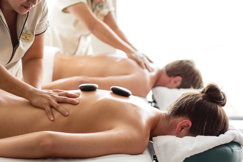 Couple receiving massages at spa with hot stones on backs.