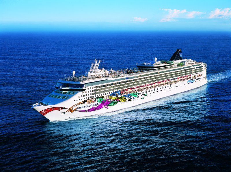 Cruise ship sailing on blue ocean, colorful artwork on hull.