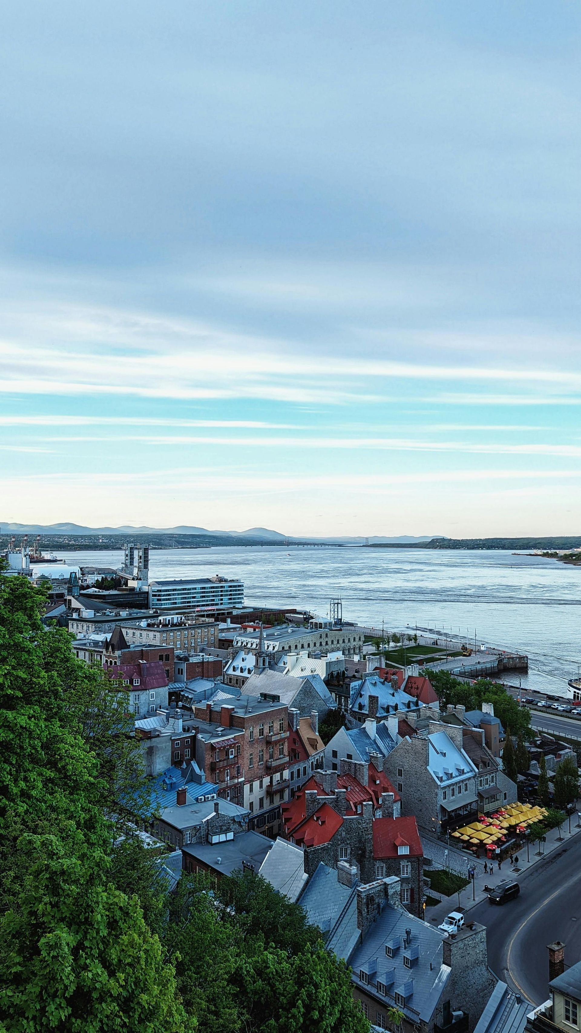 Cityscape with colorful buildings, river, and cloudy sky.