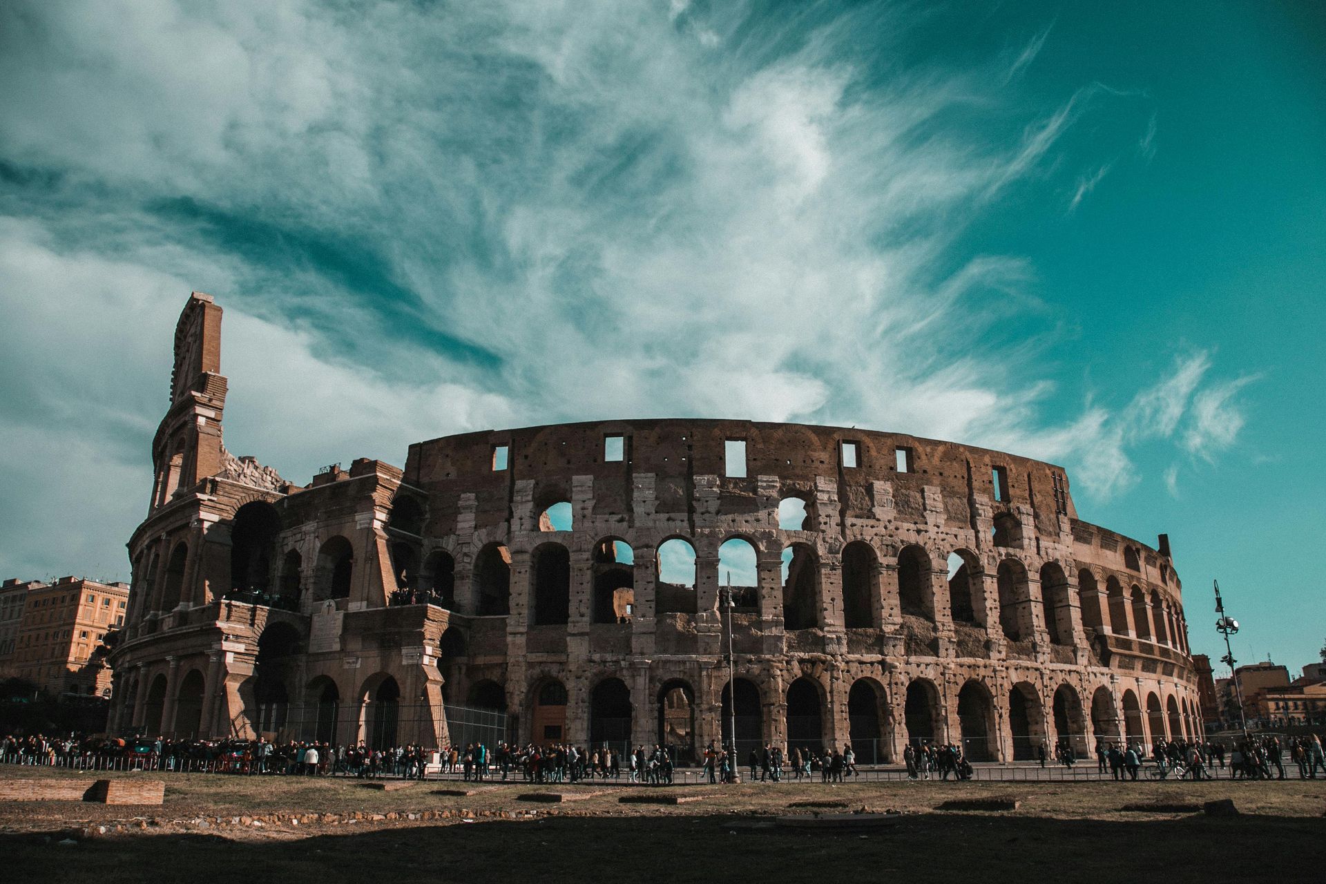 Colosseum ruins in Rome, Italy, under a partly cloudy blue sky.