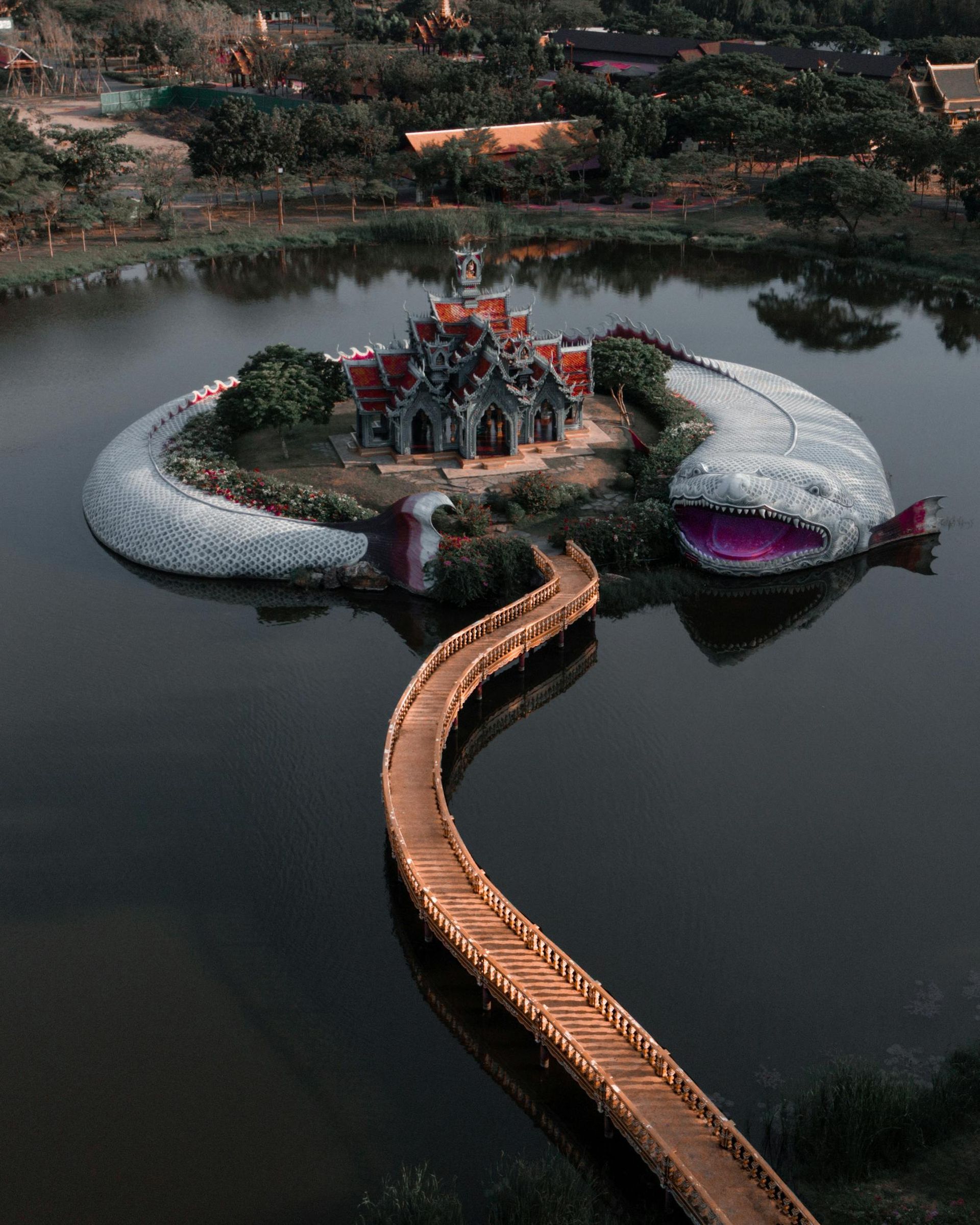 Temple on a lake shaped as a giant serpent with a bridge leading to it.