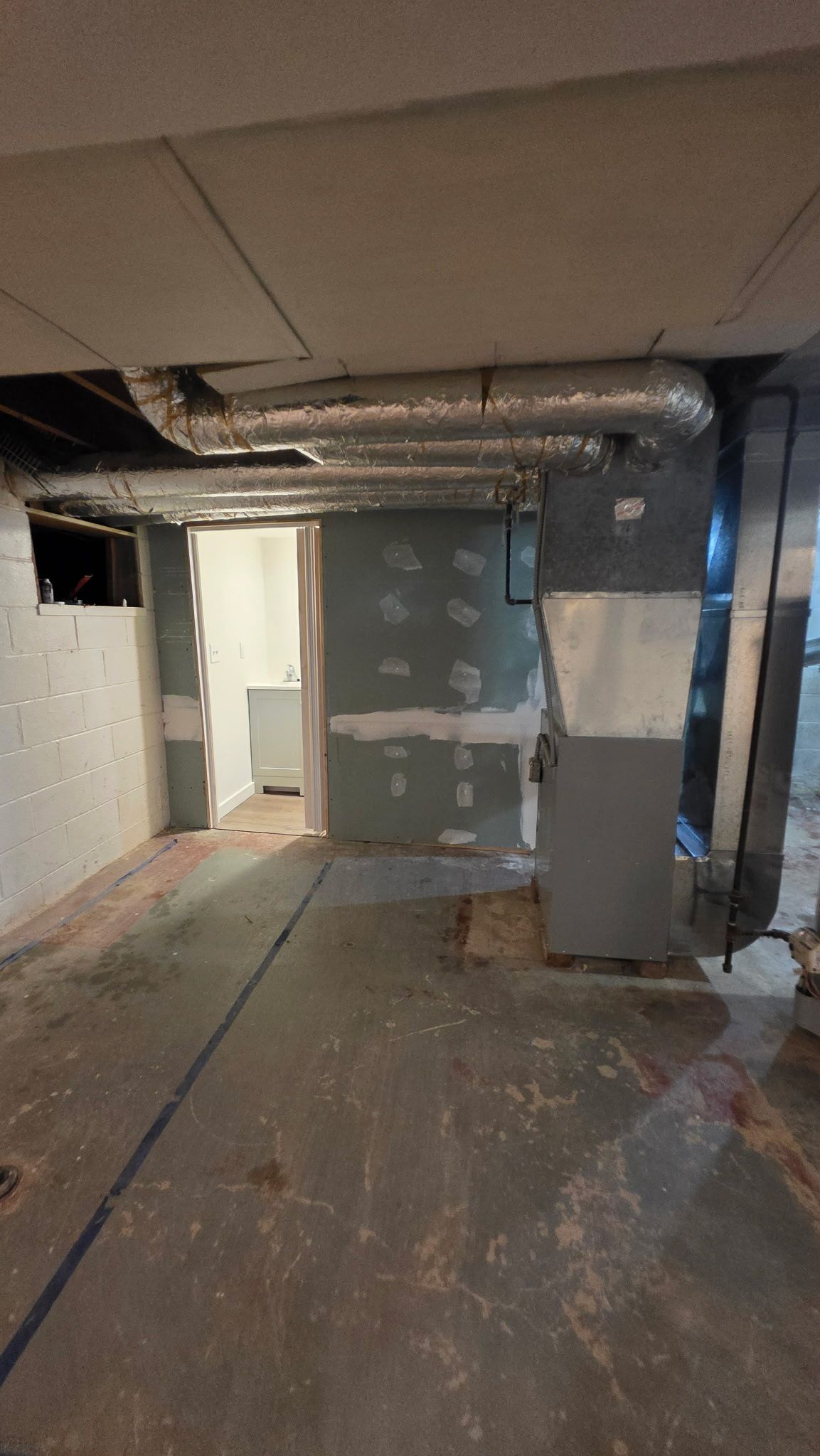 Basement interior with unfinished walls, ductwork overhead, and concrete floor.