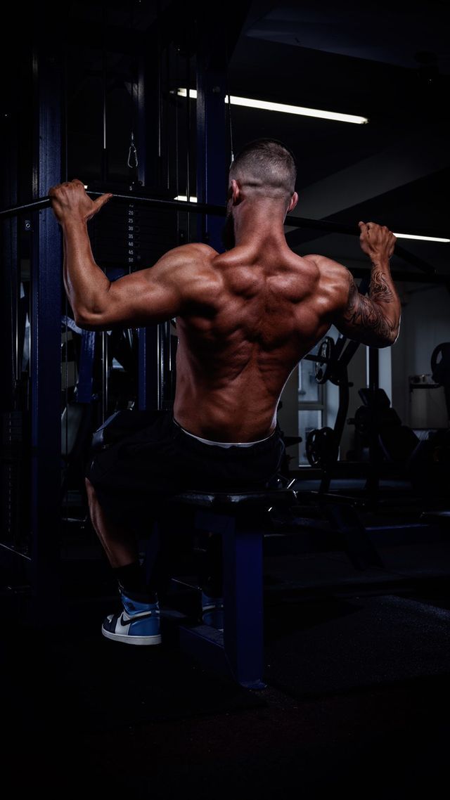 a bodybuilder is flexing his muscles in a gym .
