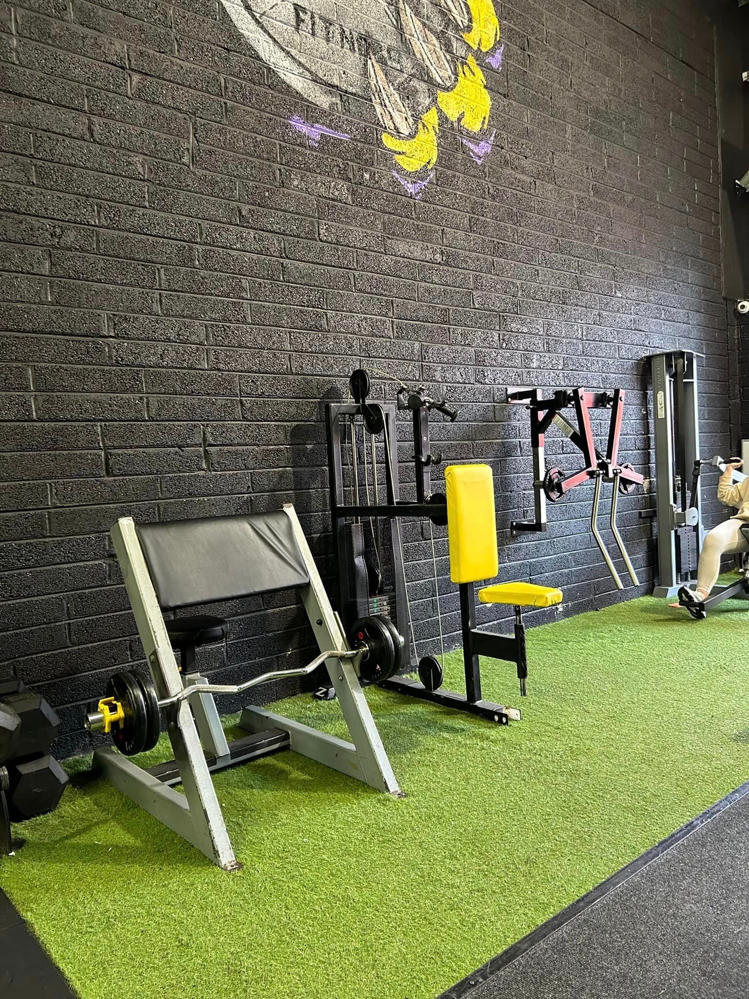 a gym with a lot of equipment and a brick wall .
