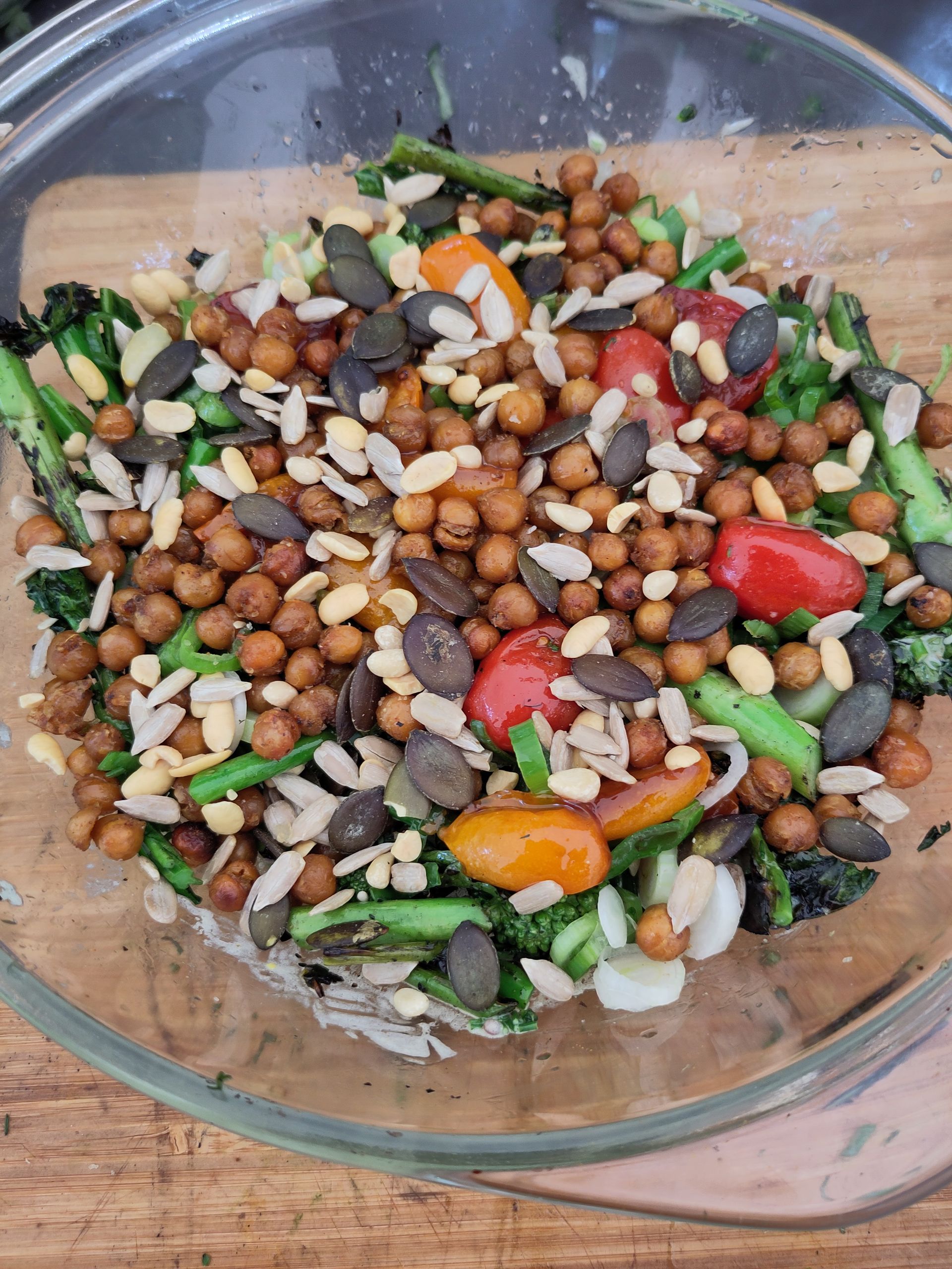 Een salade met kikkererwten, broccoli, tomaten en amandelen in een glazen kom