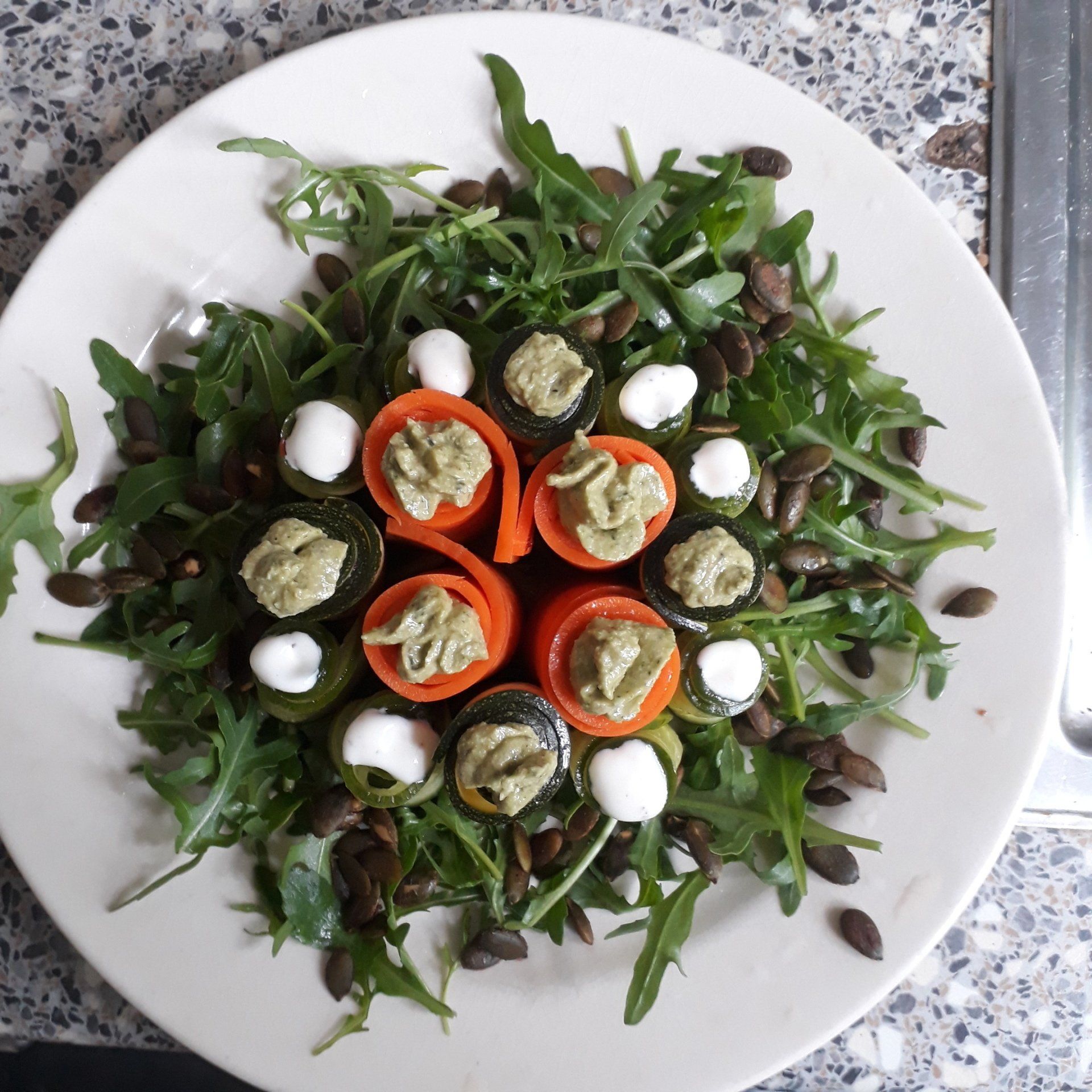 Een wit bord met daarop een salade van groenten en noten