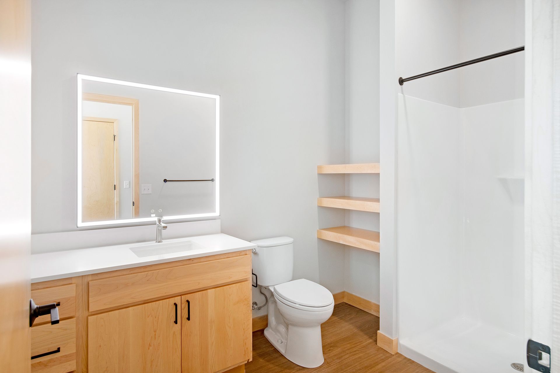 A bathroom with a toilet , sink , mirror and shower.