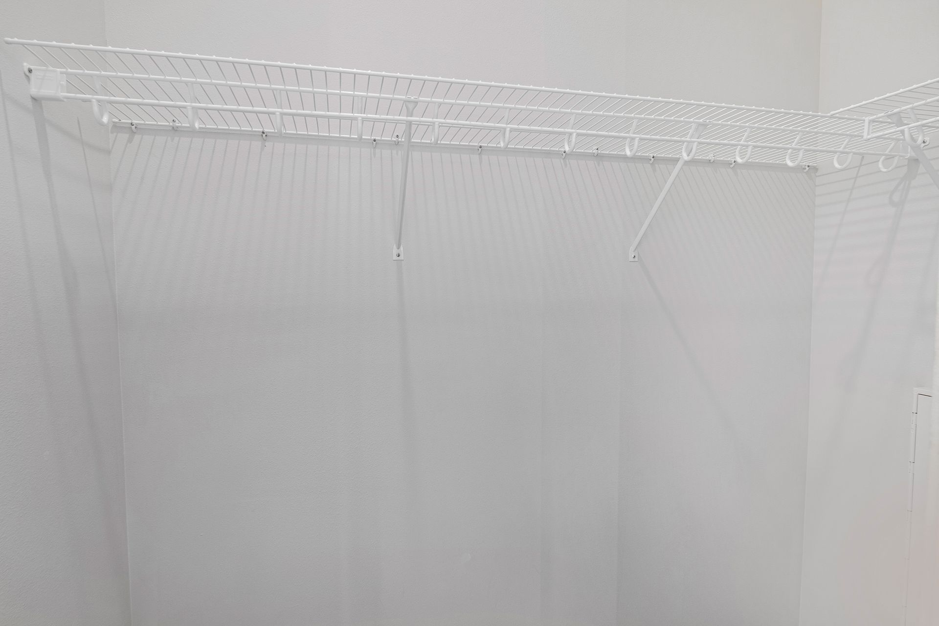 An empty closet with a white wire rack on the wall.