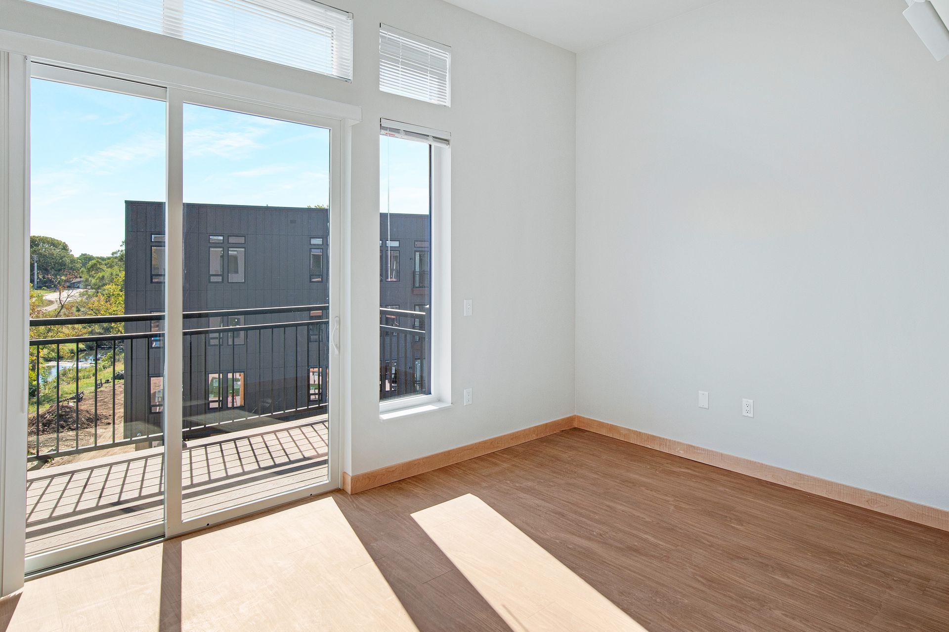 An empty room with a balcony and sliding glass doors