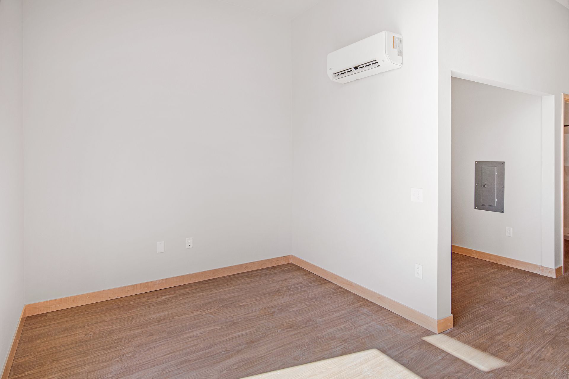 An empty room with a carpeted floor and a wall mounted air conditioner.