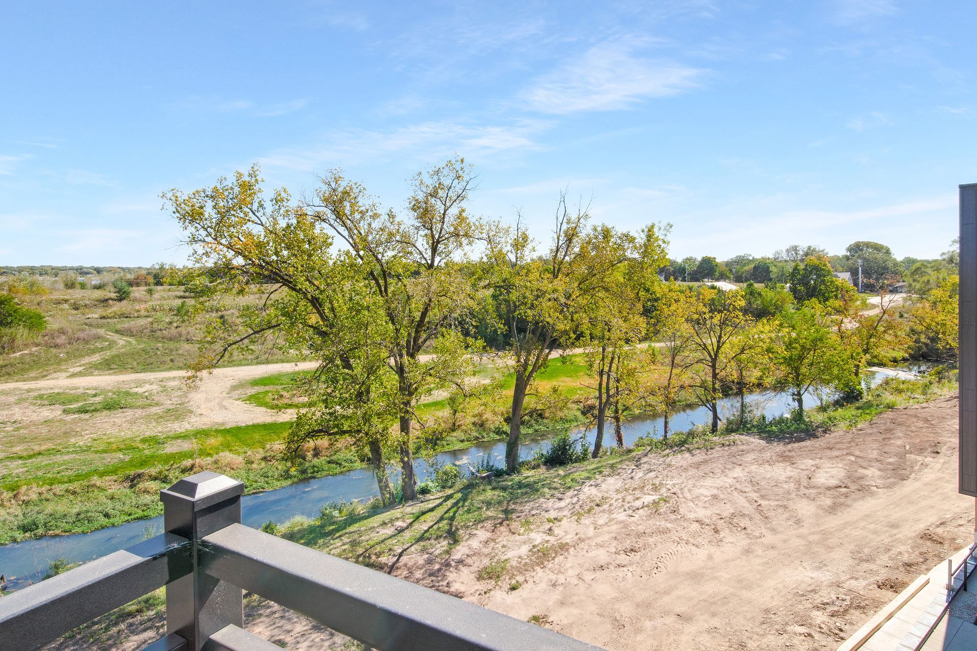 A view of a river from a deck with trees in the background.