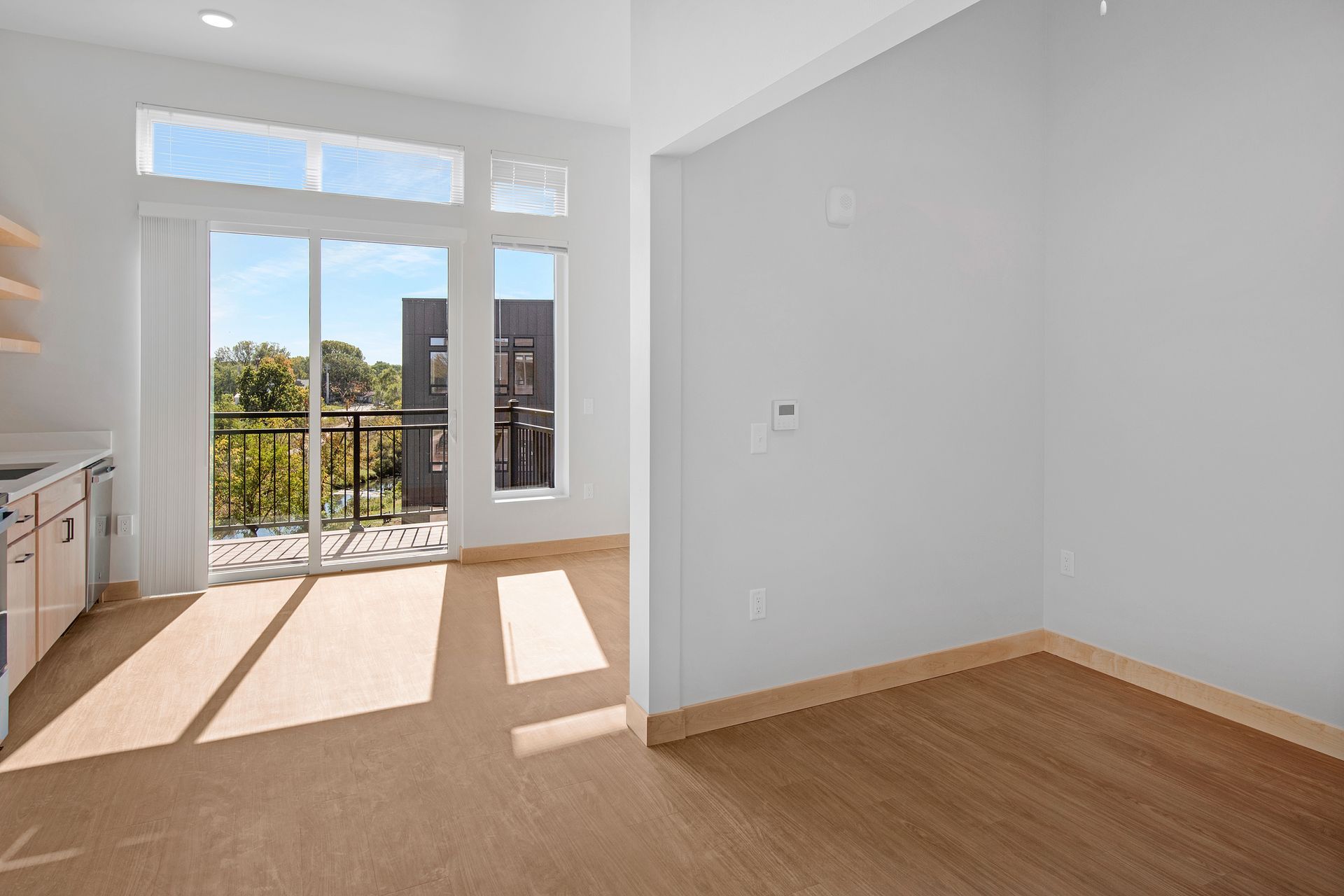 An empty room with a sliding glass door and a balcony.