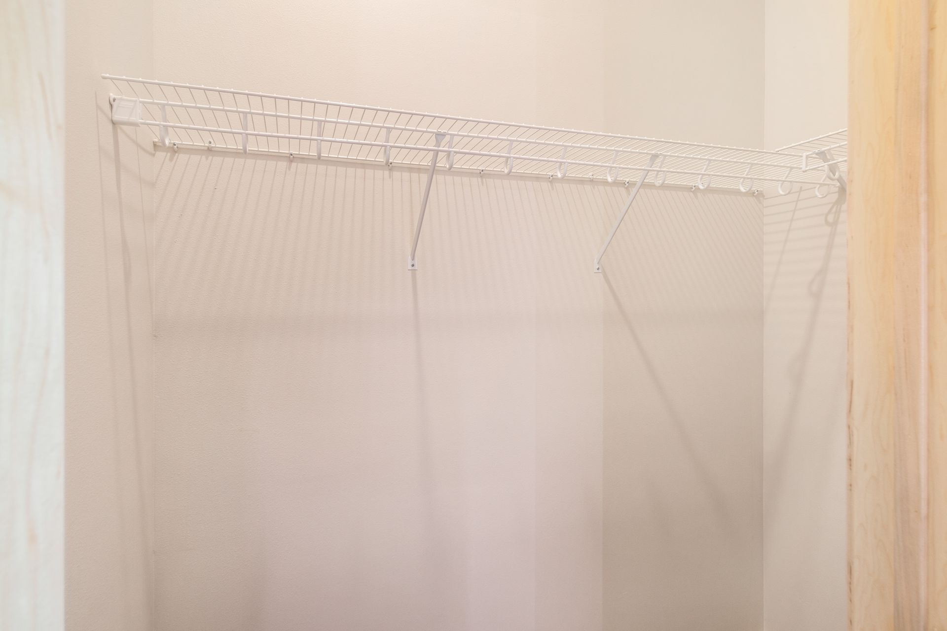 An empty closet with a metal shelf and a wooden door.