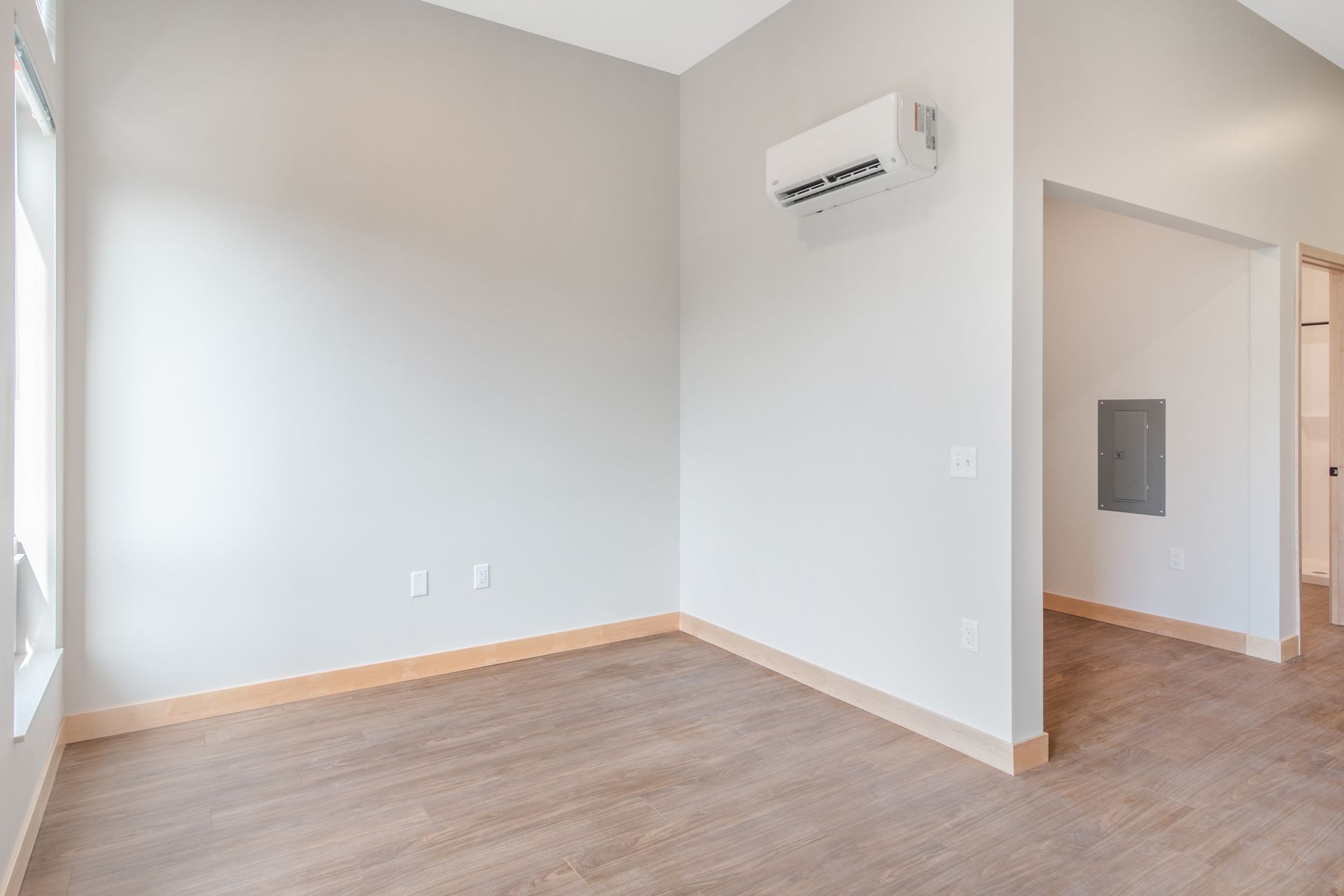 An empty room with hardwood floors and a wall mounted air conditioner.