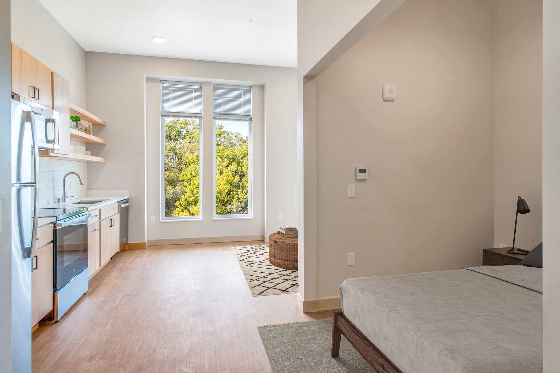 A bedroom with a bed and a kitchen with a refrigerator.