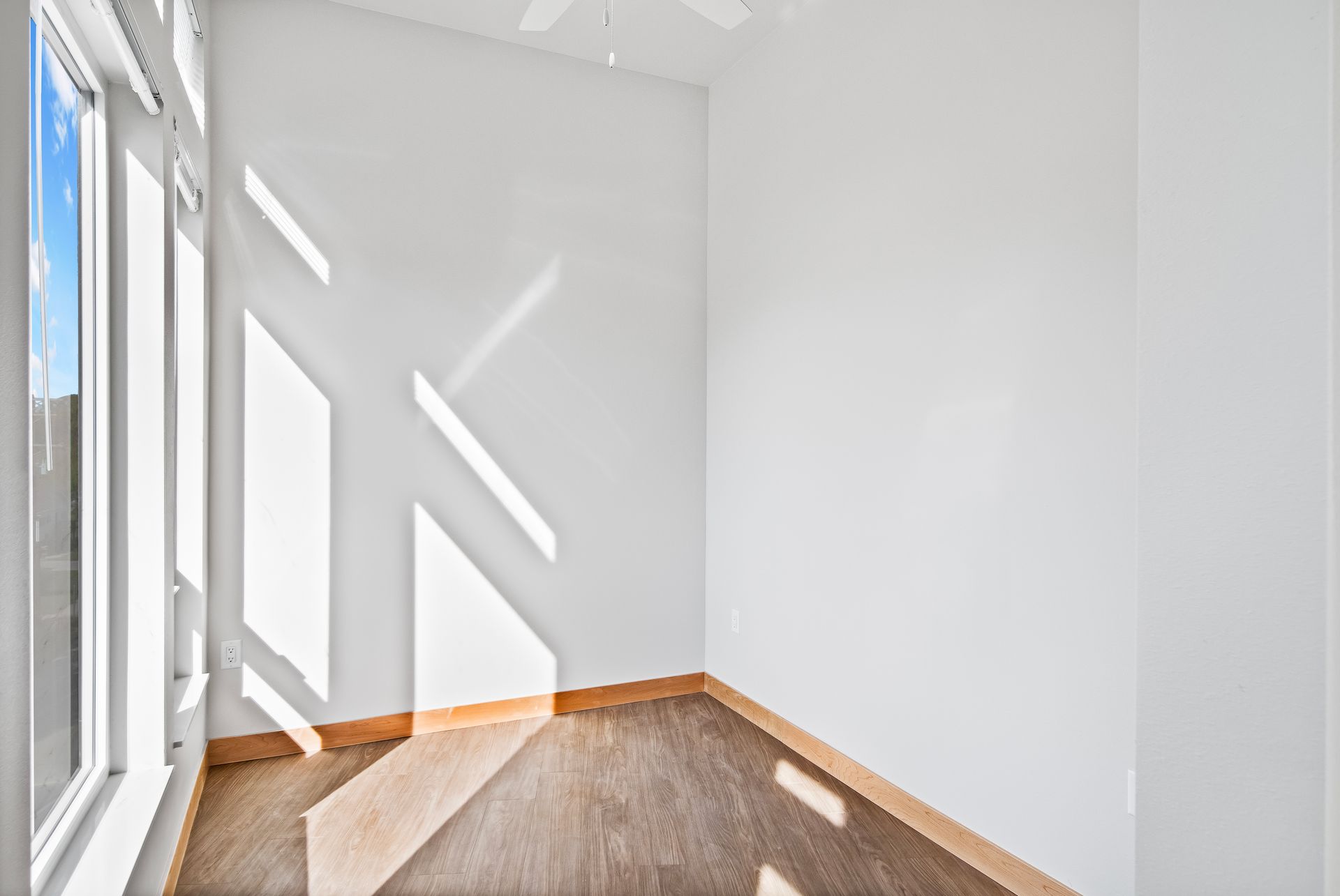 An empty room with a ceiling fan and a window.