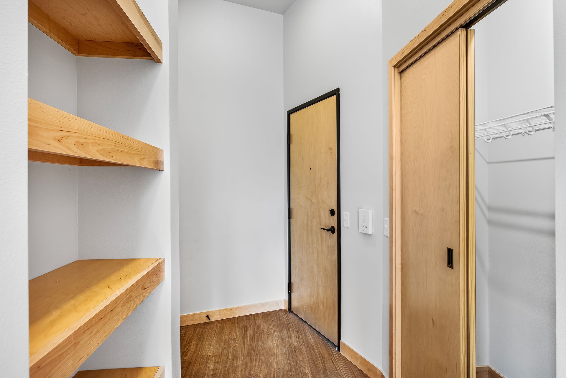 A hallway with wooden shelves and a wooden door.
