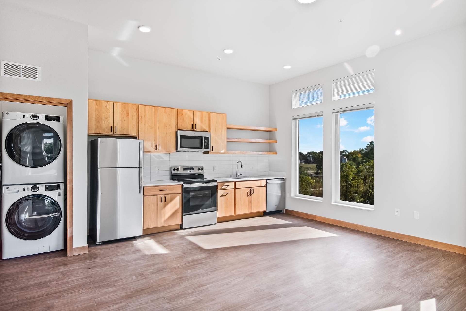 A kitchen with a refrigerator , washer and dryer stacked on top of each other.