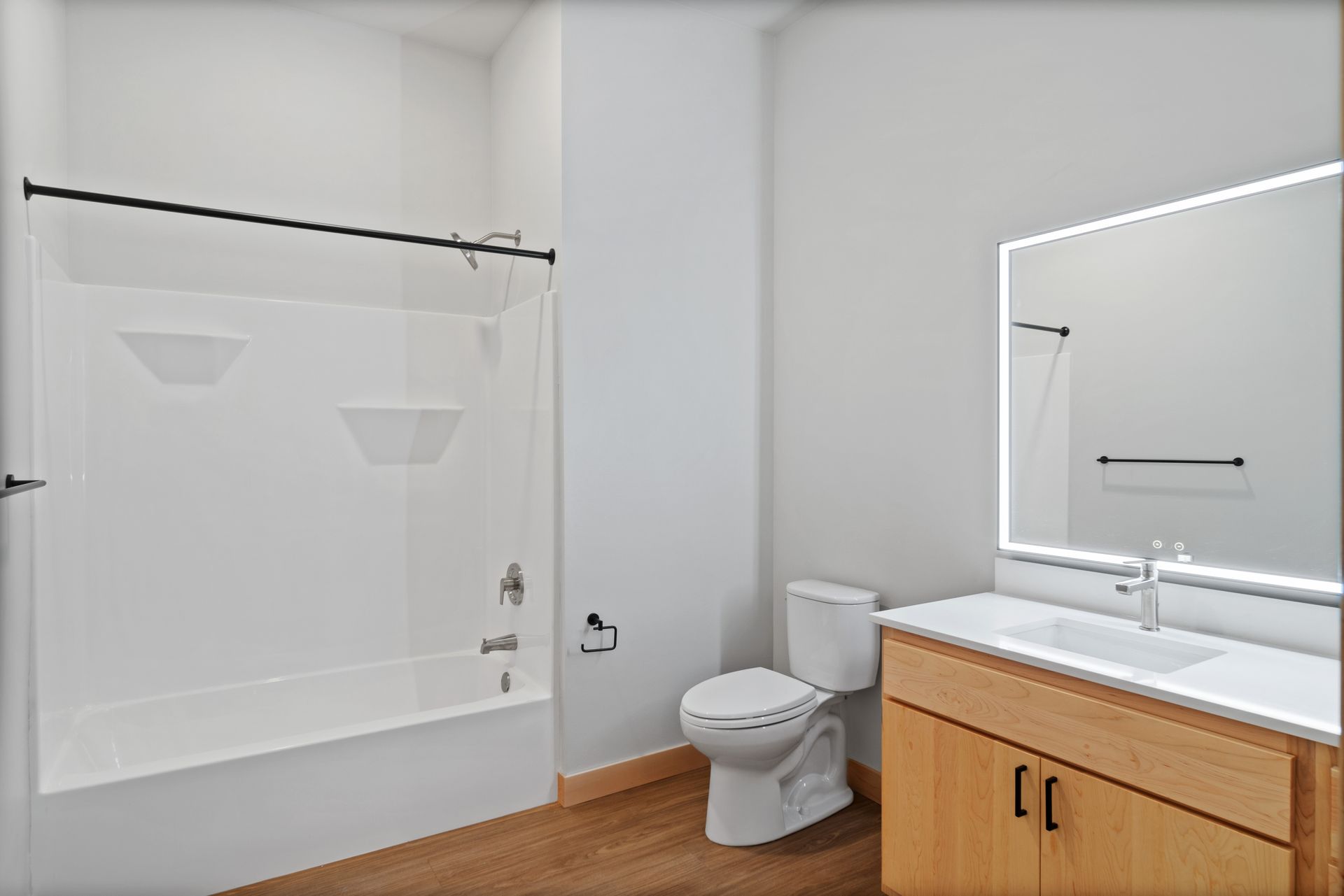 A bathroom with a toilet , sink , bathtub and mirror.