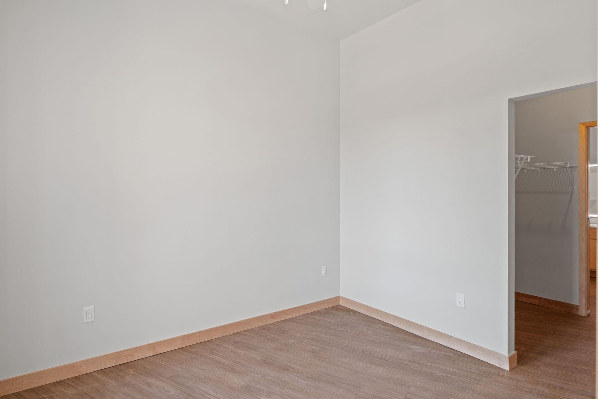 An empty room with a wooden floor and white walls.