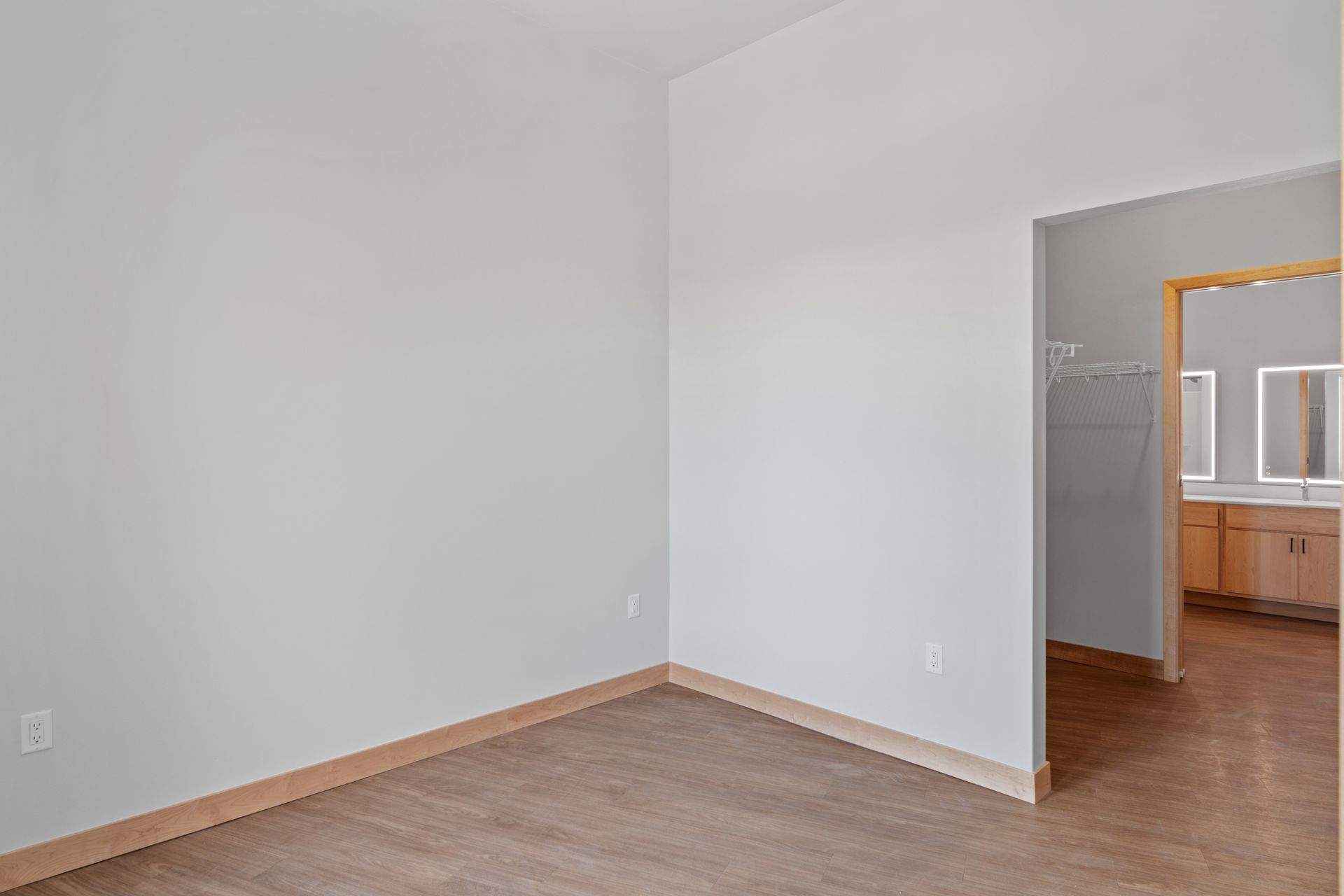 An empty room with a wooden floor and white walls.