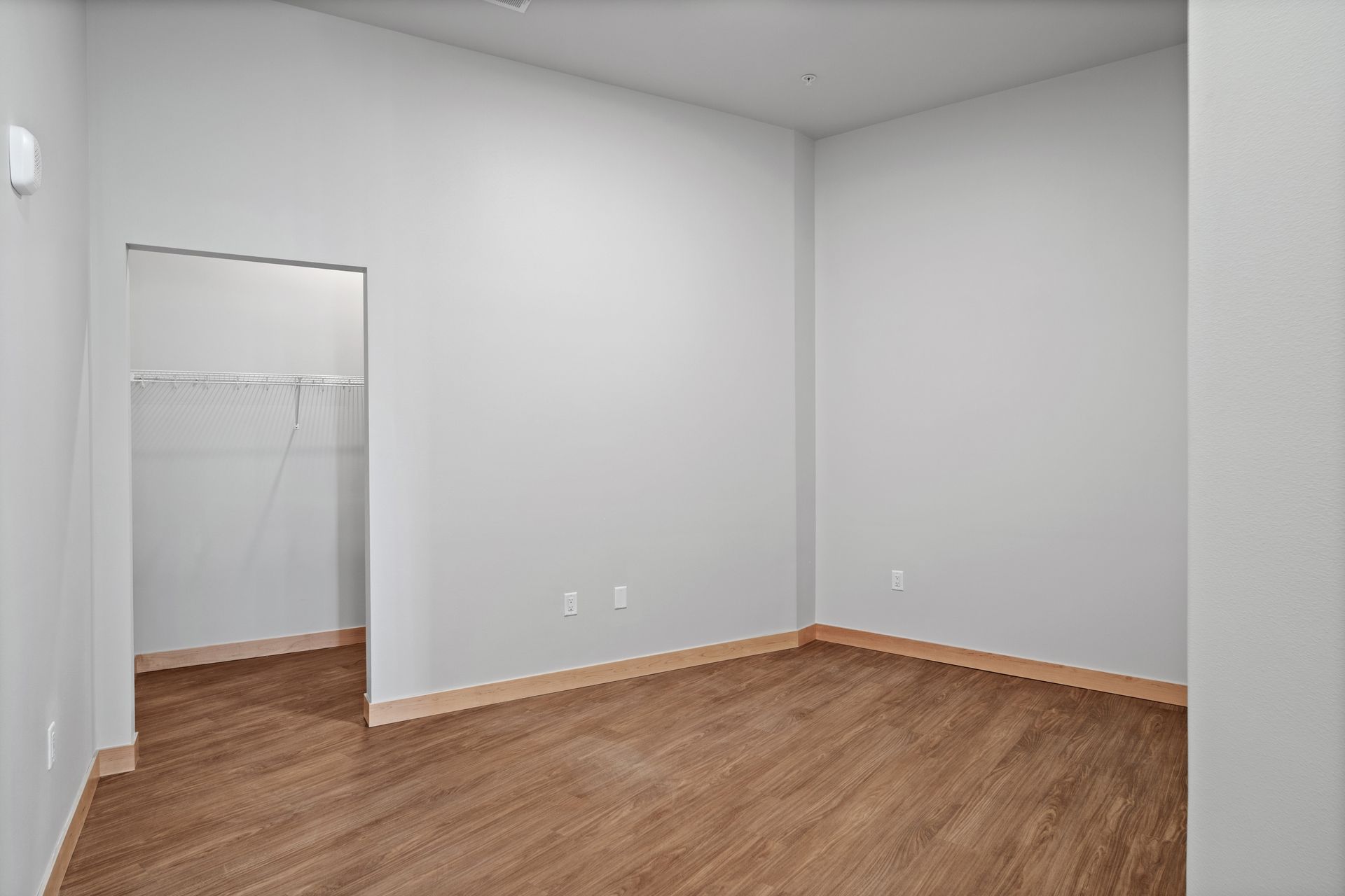 An empty room with hardwood floors and a walk in closet.