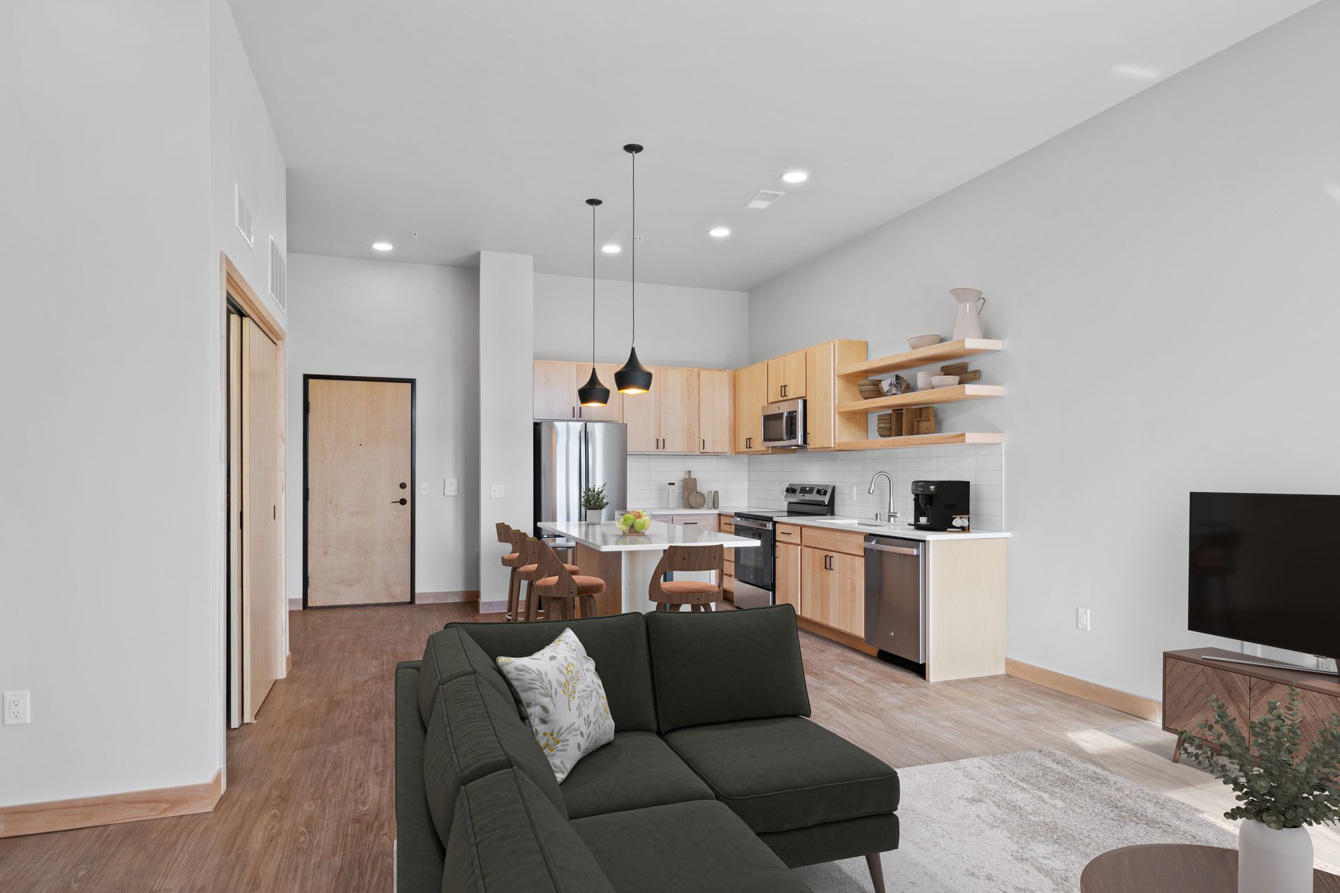 A living room with a couch , television , and kitchen.