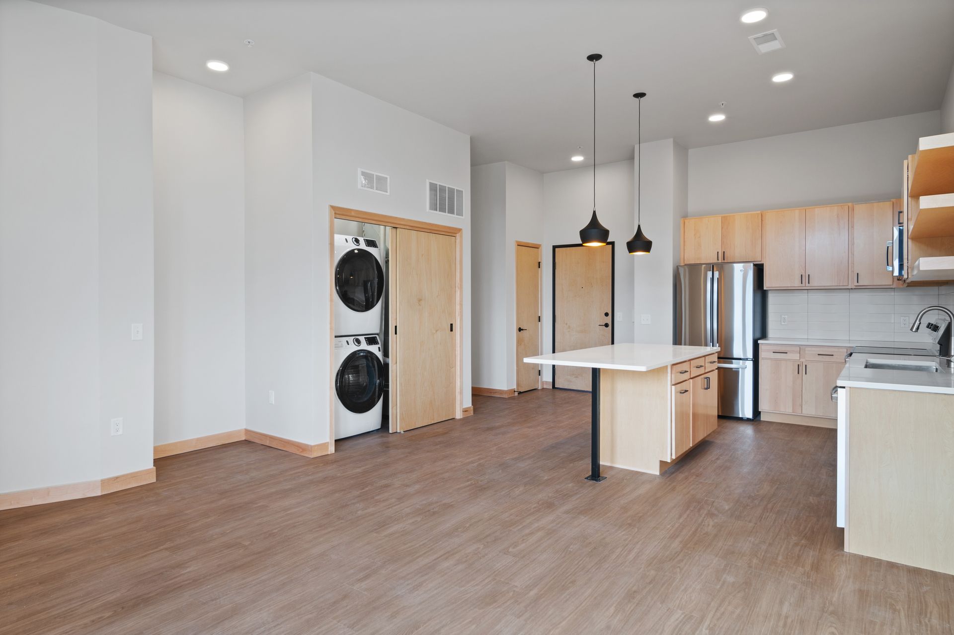 An empty kitchen with a washer and dryer in the corner.