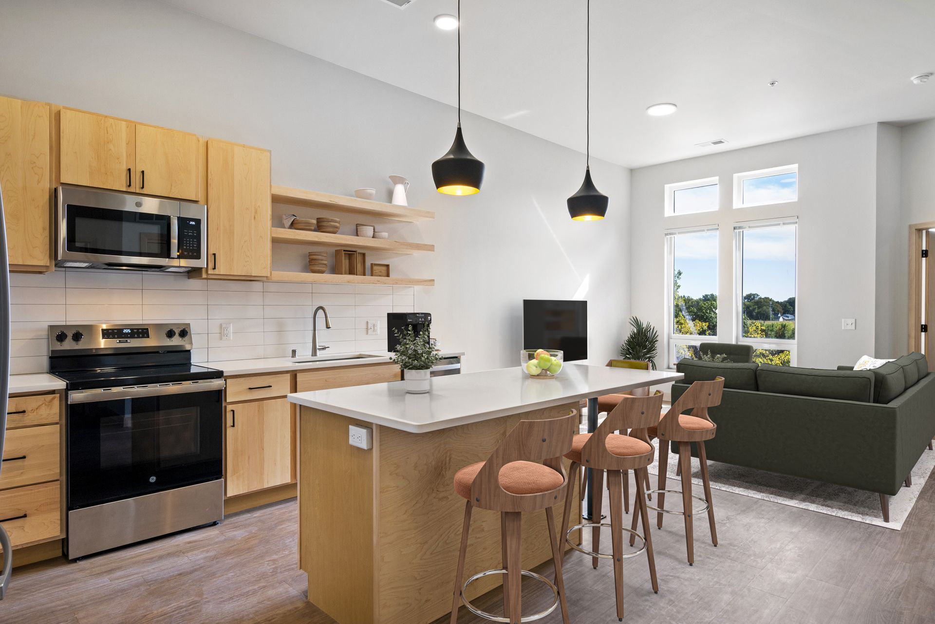 A kitchen with stainless steel appliances , wooden cabinets , a large island and stools.