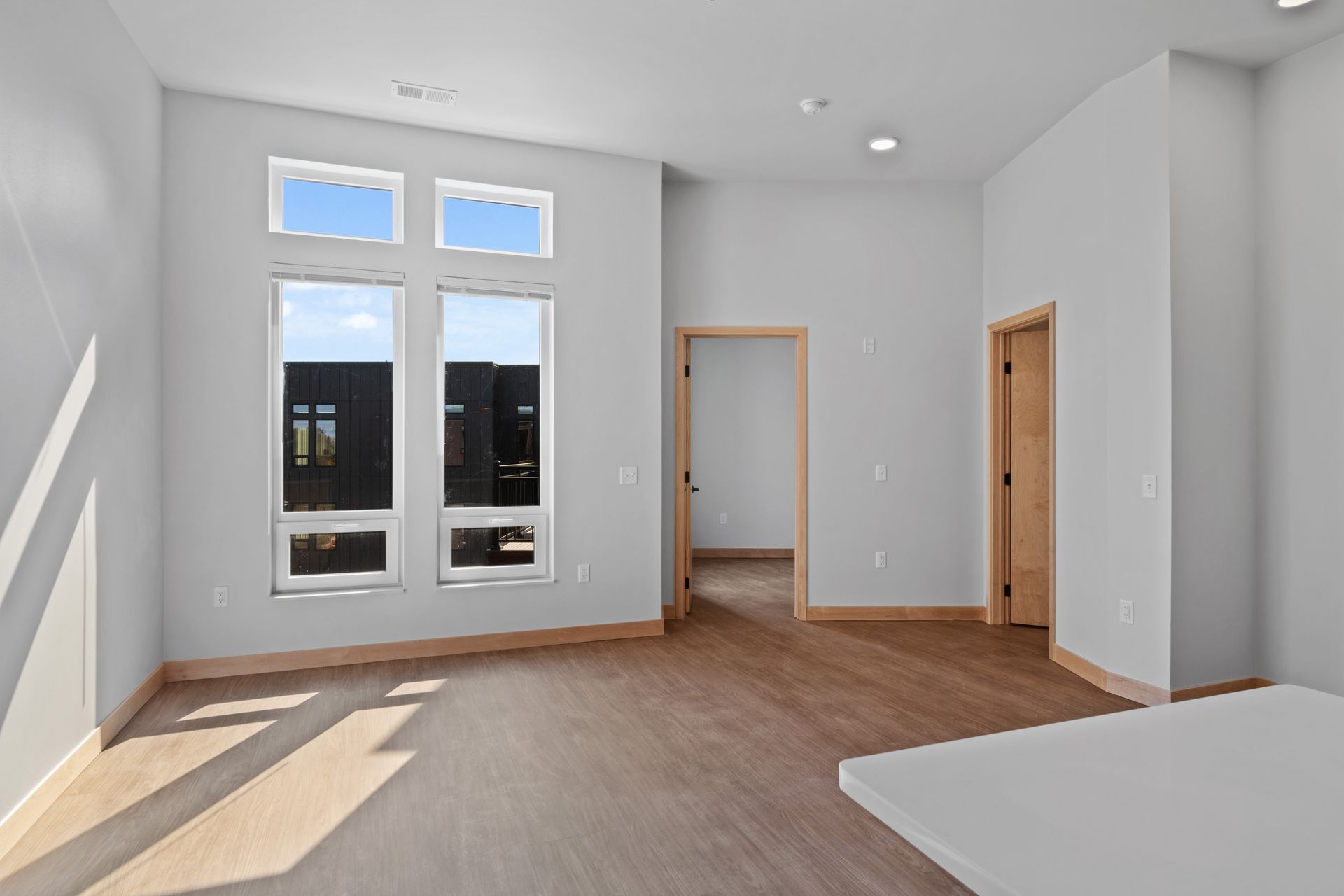 An empty living room with two windows and a wooden floor.